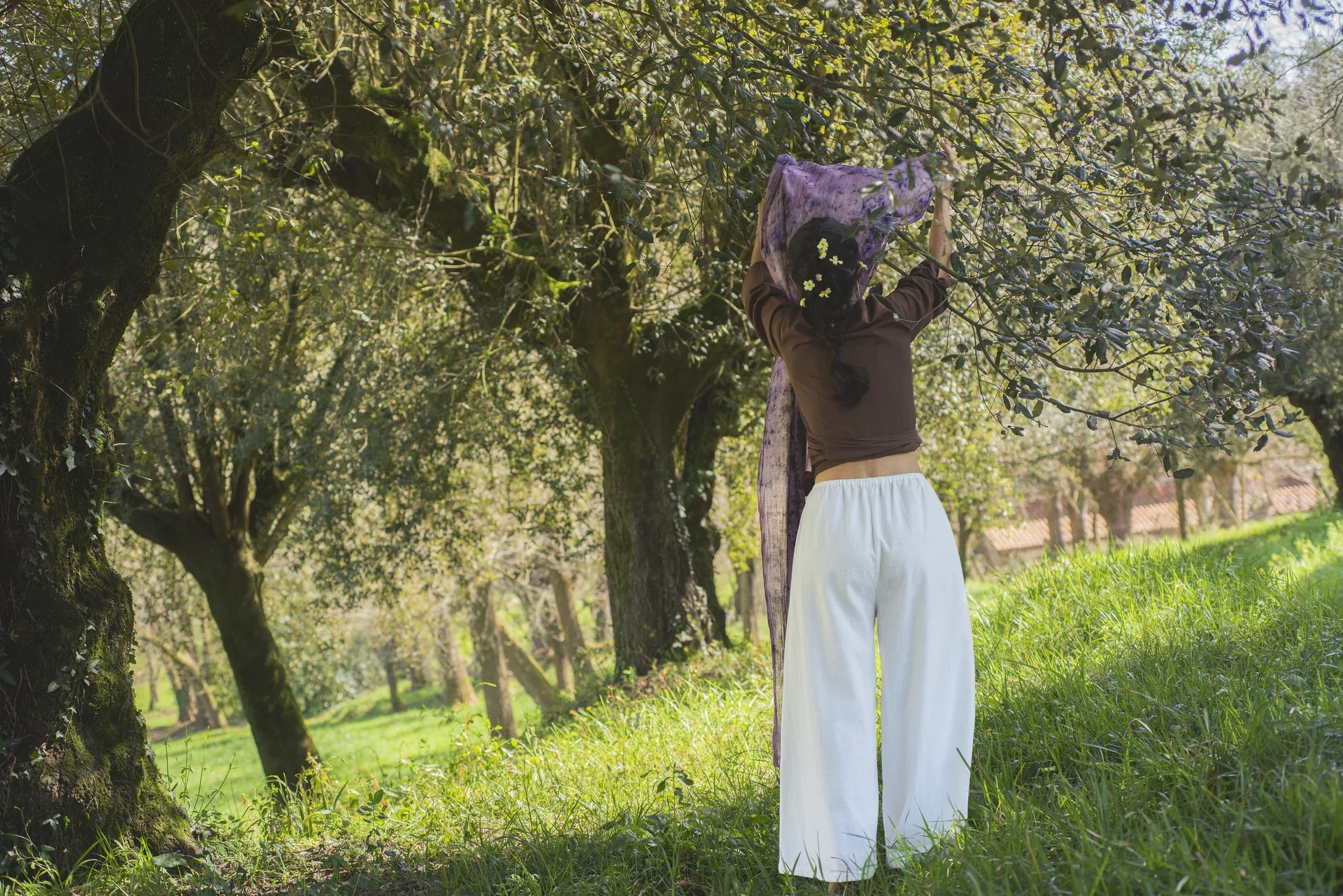 Mujer en la naturaleza vistiendo el Pantalón Orekan de pata ancha en color blanco, confeccionado en algodón orgánico y tintes naturales libres de tóxicos