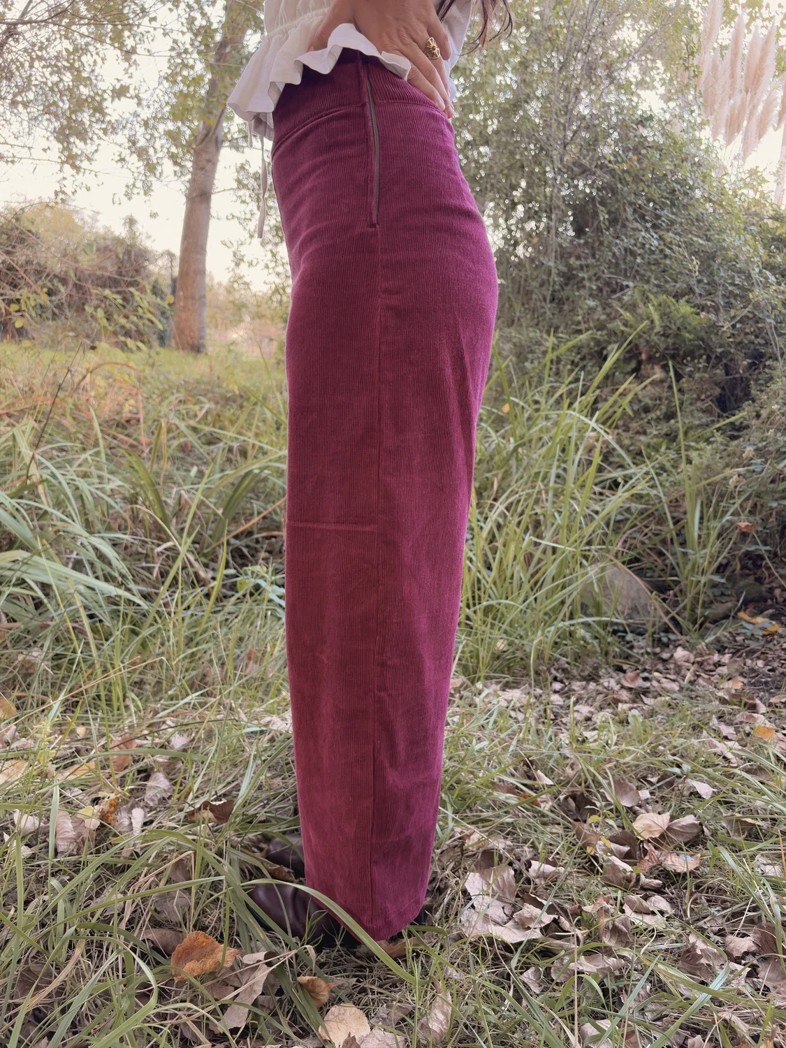 Mujer sonriente en el bosque luciendo el pantalón Indira de pana.