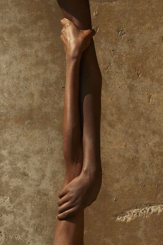 An optical illusion where two arms merge, one appearing to hold a brown object, creating a surreal visual effect.