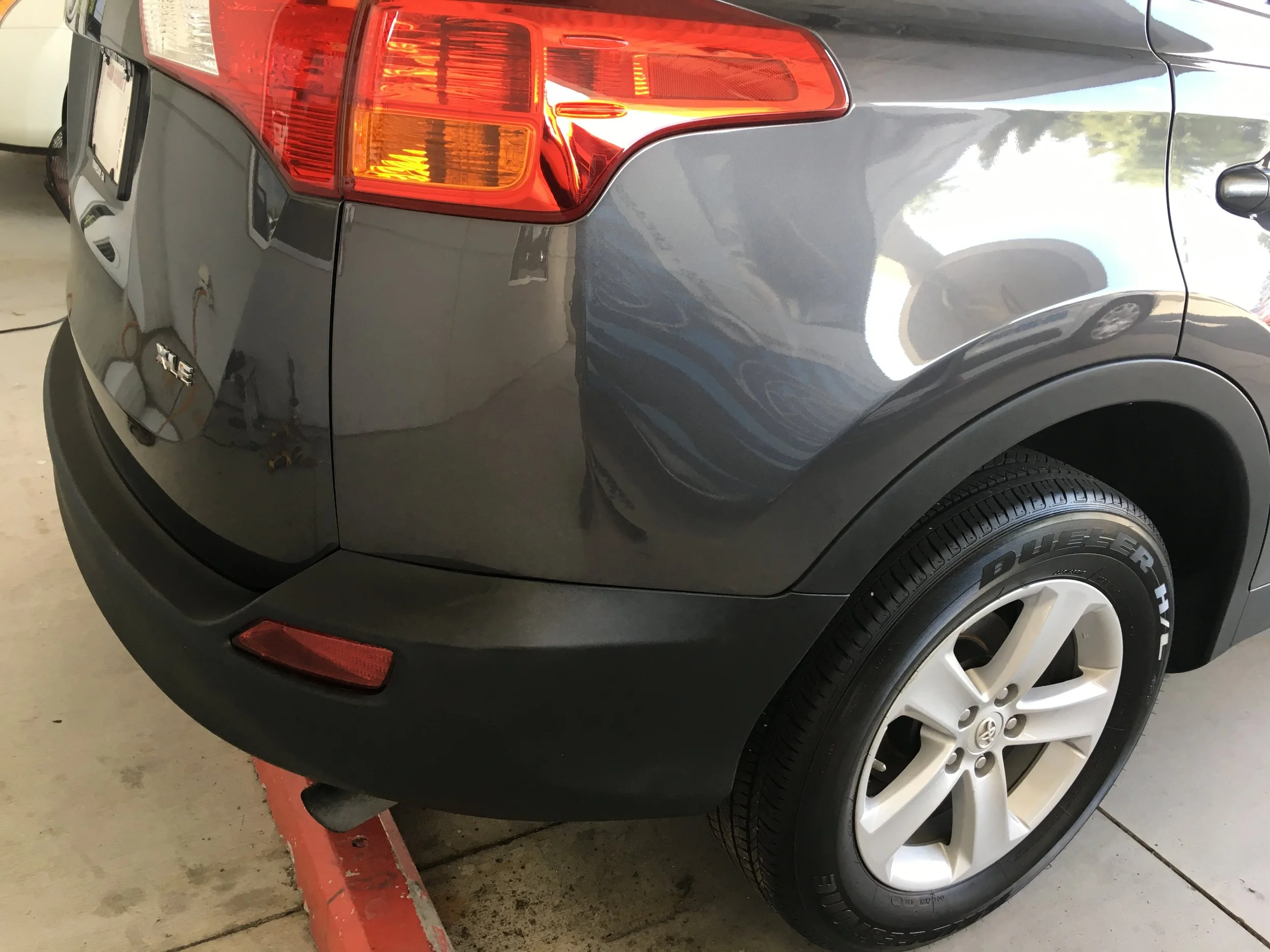 Rear and side view of a gray Toyota SUV, showing the taillight, wheel with PowerHitter tire, and parked on a concrete garage floor.