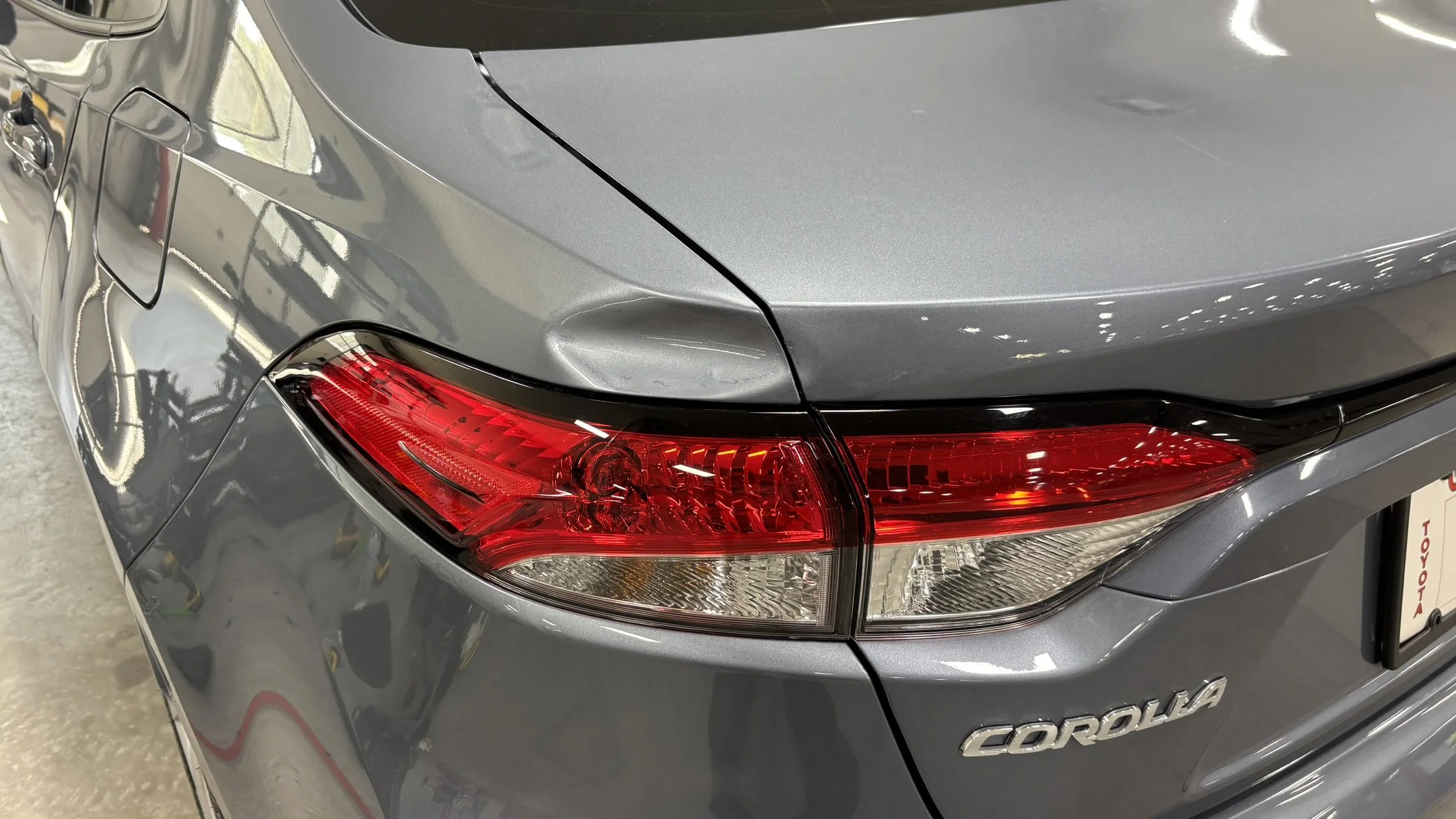 Rear end of a gray Toyota Corolla with visible tail light, trunk, and rear bumper.