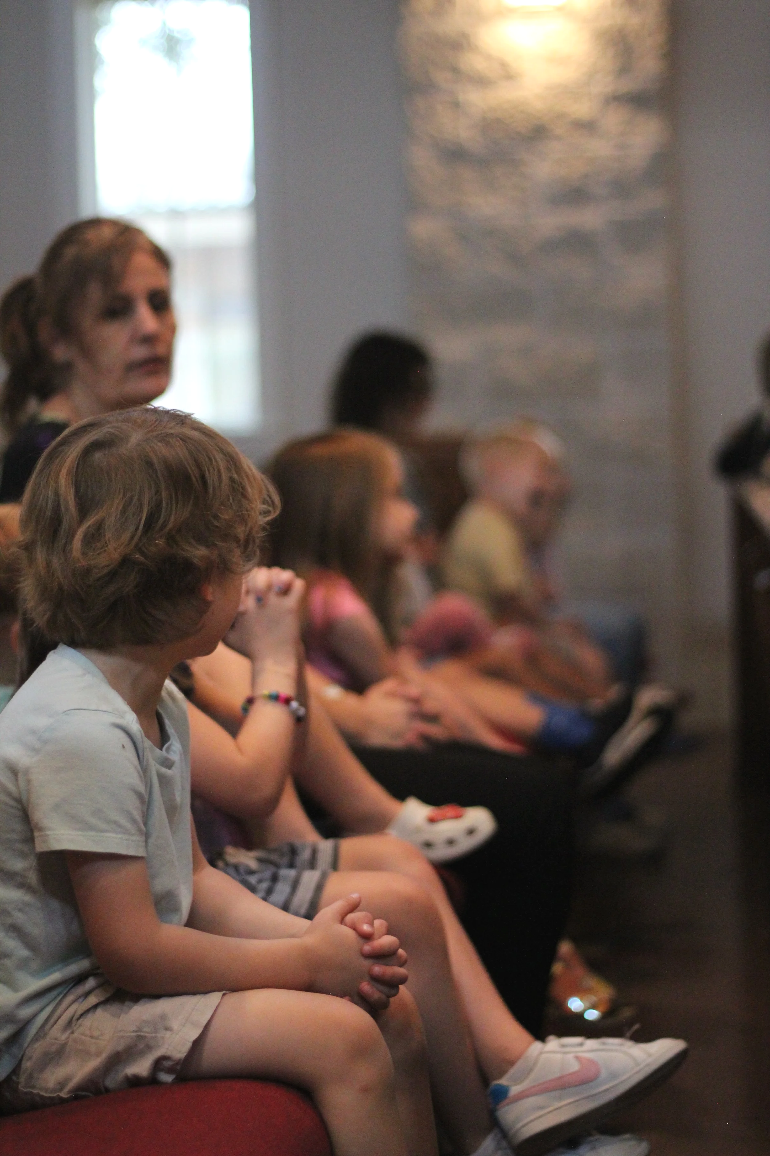 Children and teachers sitting in a row, attending weekly Wednesday Chapel.