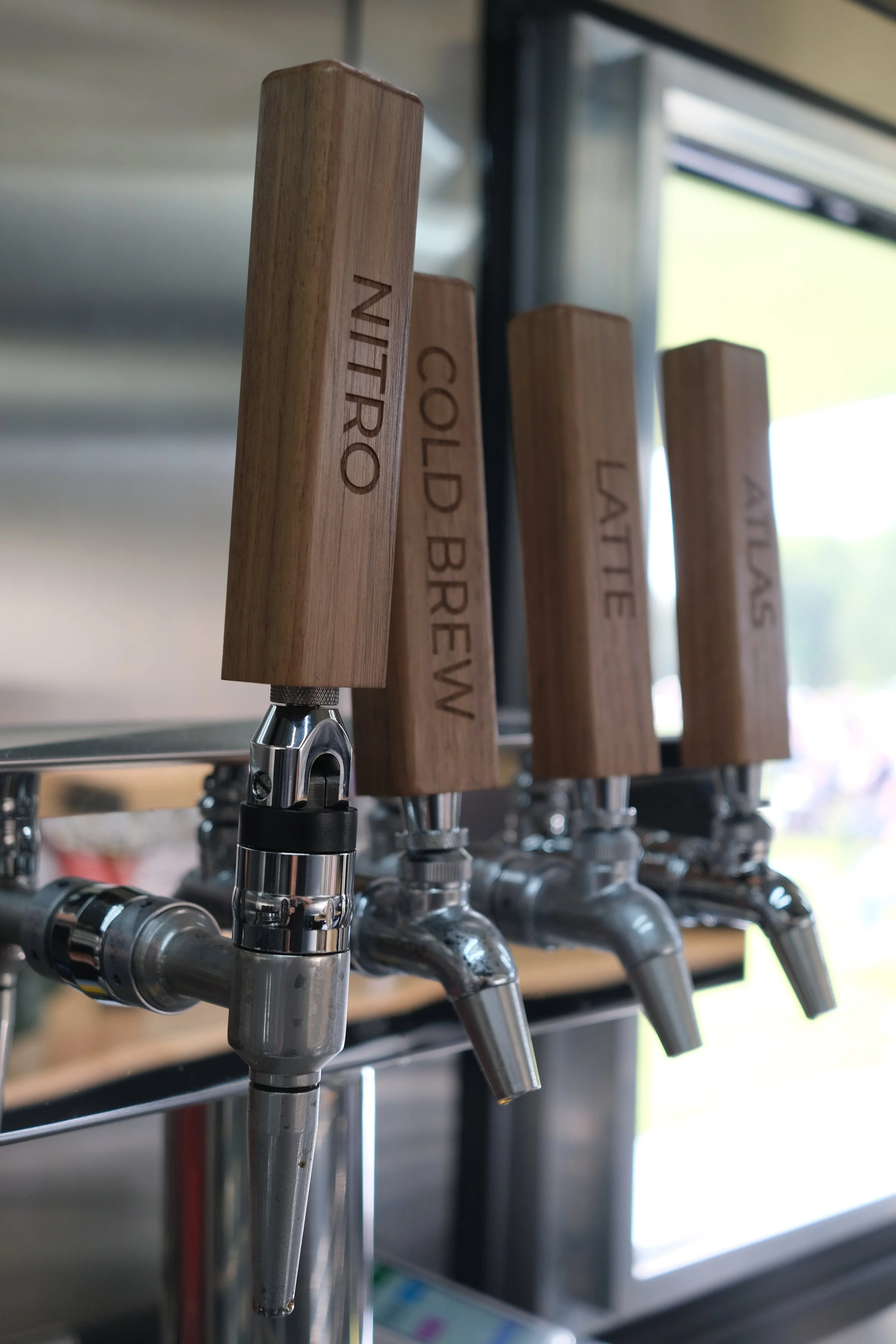 Beer taps with wooden handles labeled Nitro, Cold Brew, Latte, and Americano.