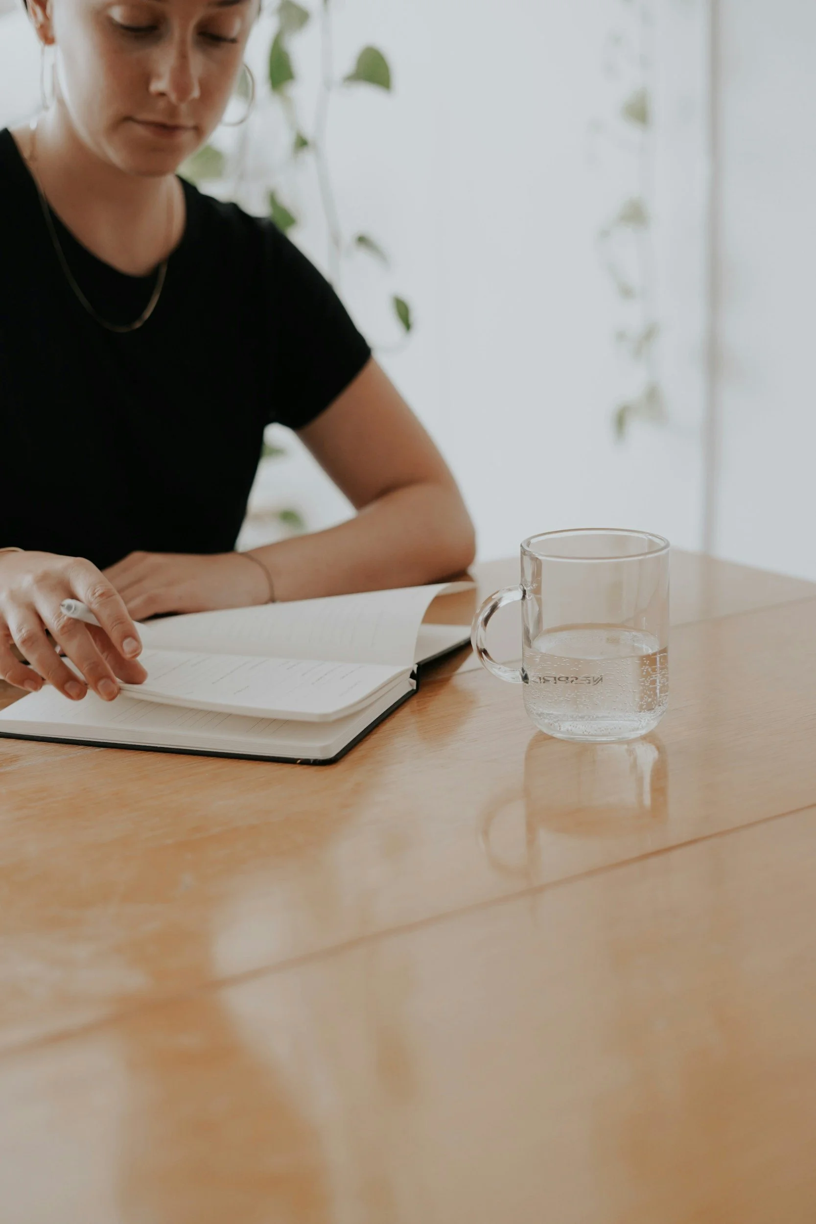 A woman sitting quietly with a journal, looking thoughtful