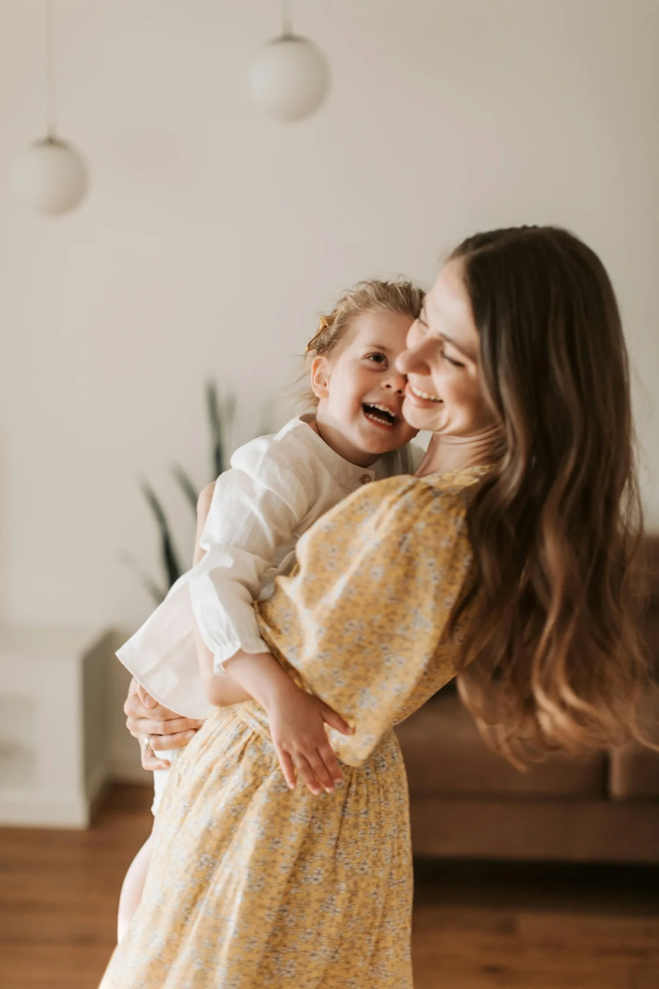 A woman with long wavy brown hair holding her smiling child.
