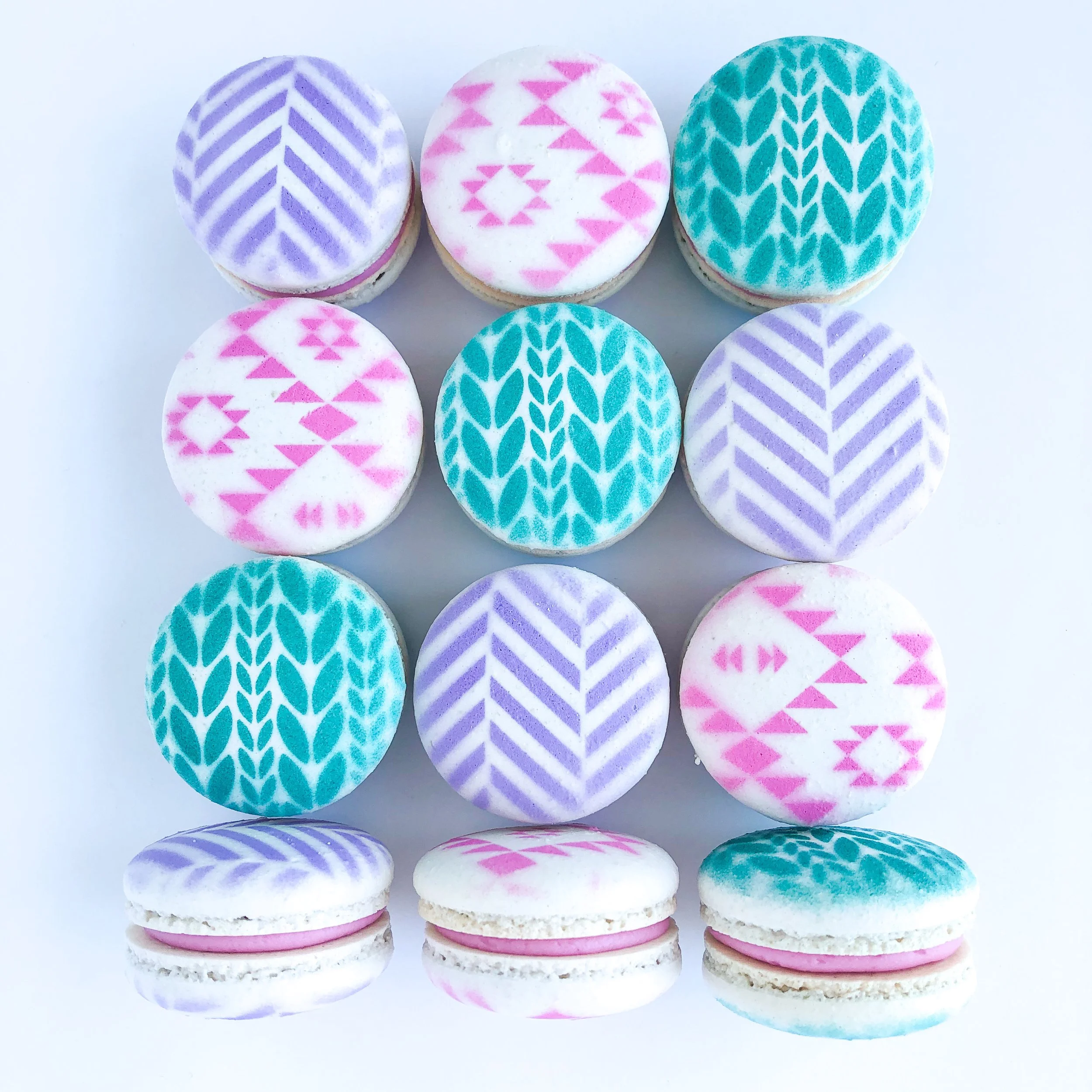 Colorful macarons with pink, purple, and teal geometric patterns on white backgrounds arranged in a grid.