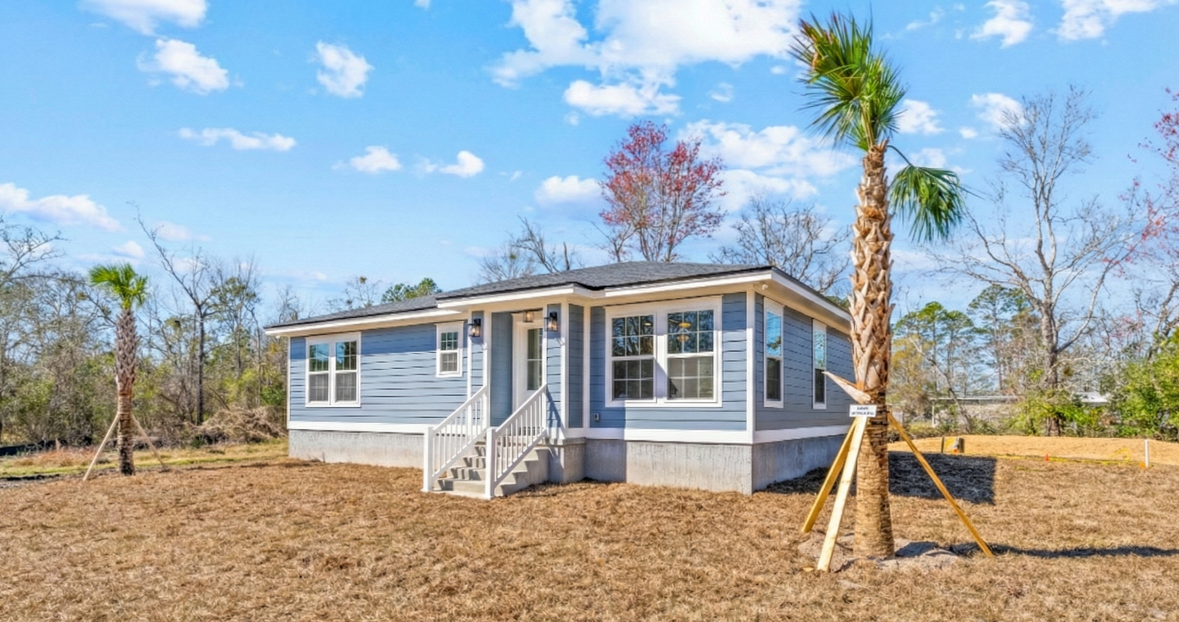 New blue house under construction with palm trees and a partly cloudy sky