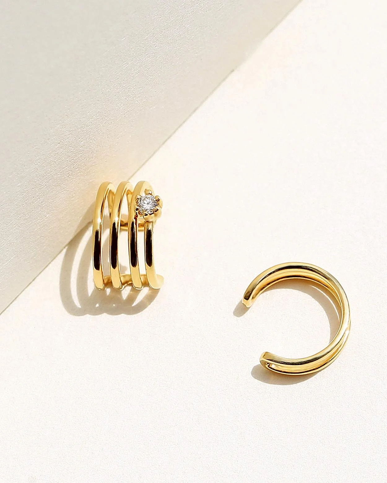 Set of gold rings, with one featuring a small diamond, arranged on a white surface with a light shadow.
