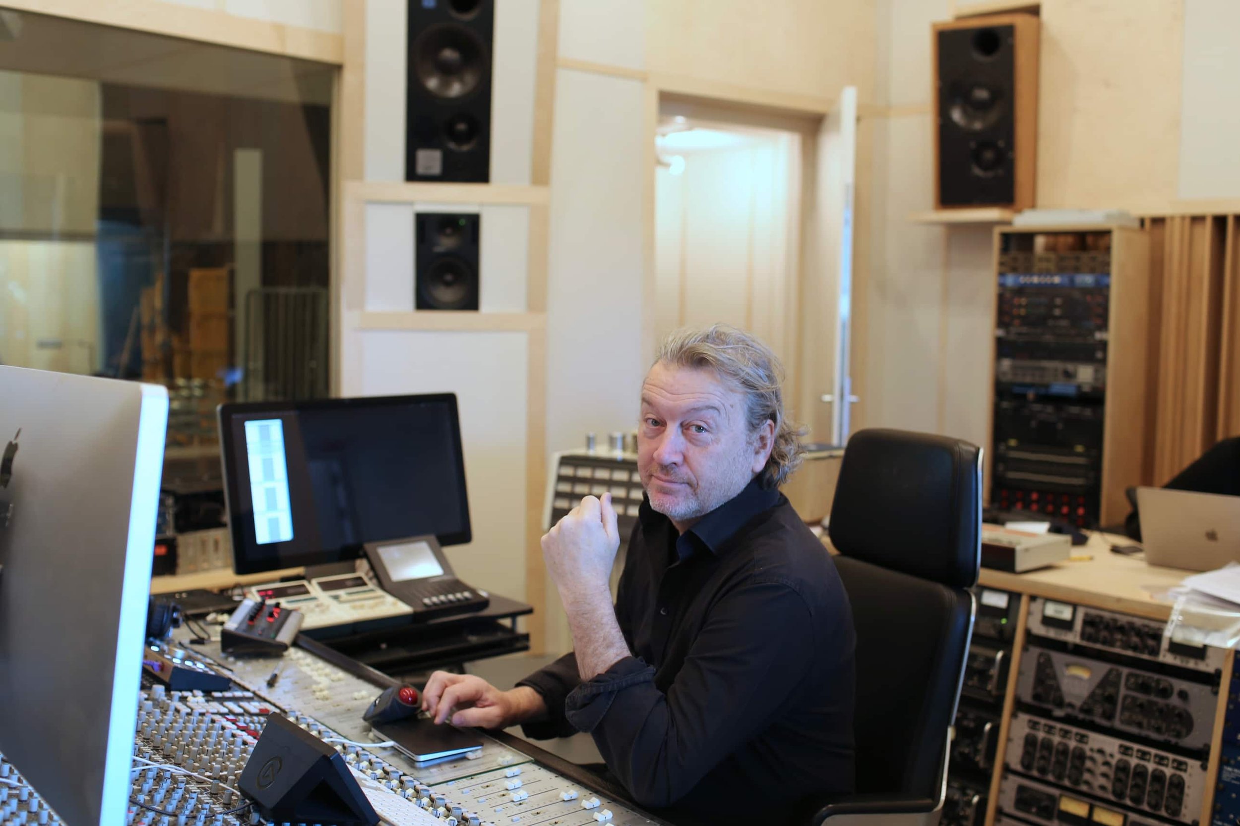 Mikel Le Roy sitting at a music mixing console in Studio Le Roy, surrounded by audio equipment and speakers.
