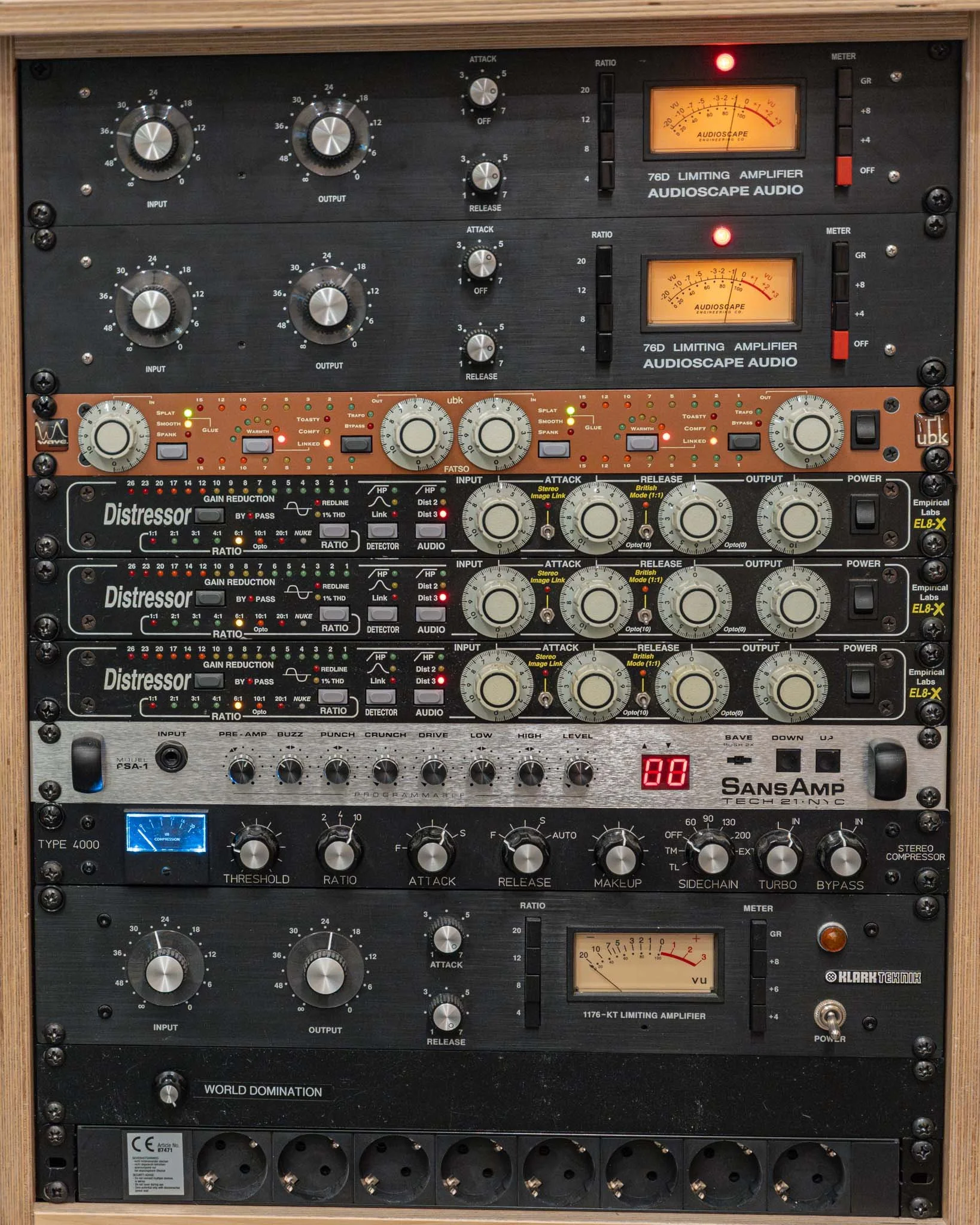 A rack of audio equipment, including amplifiers, effects processors, and a compressor.