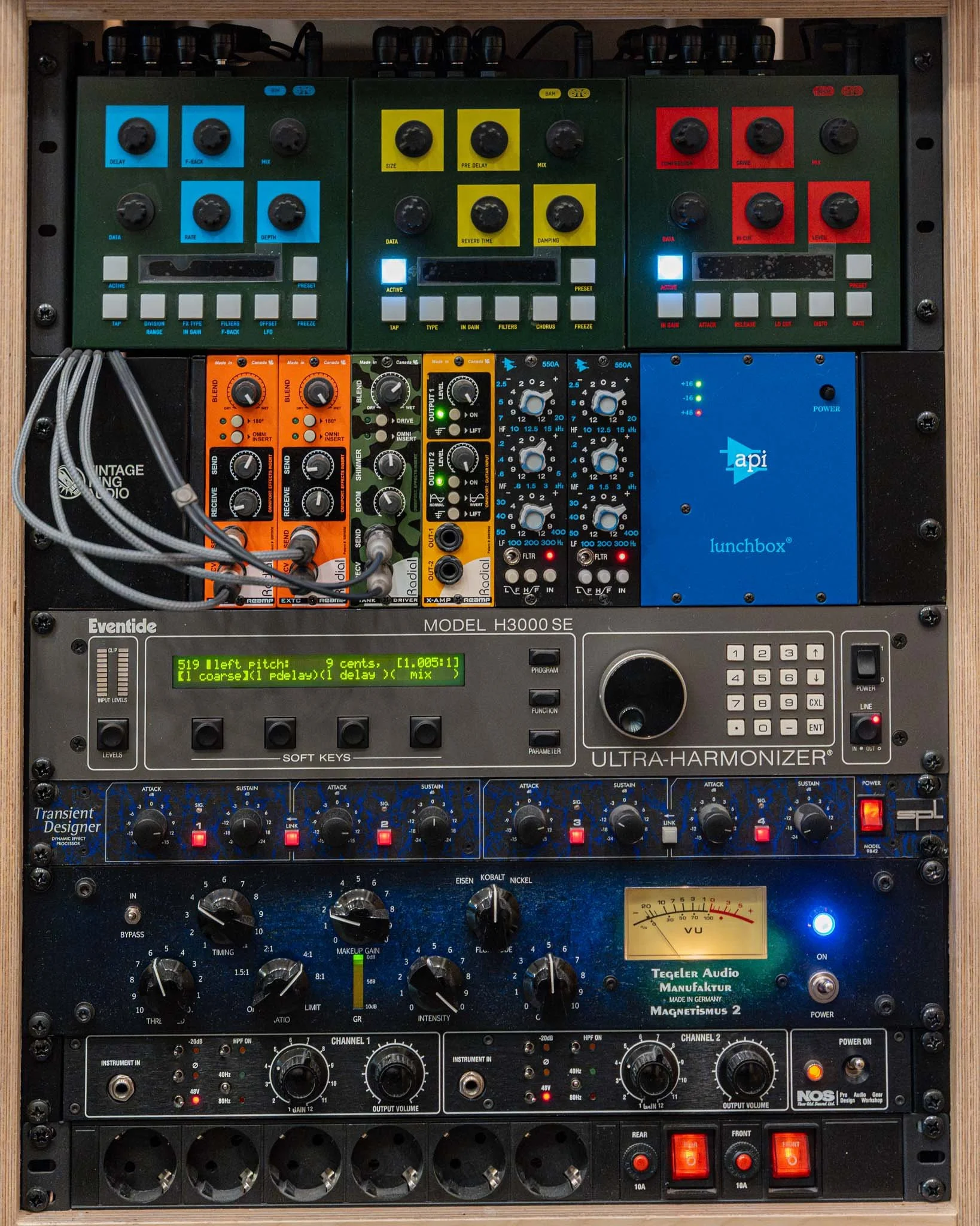 A professional audio equipment rack containing various audio processing units including effects, mixers, equalizers, and power supplies.