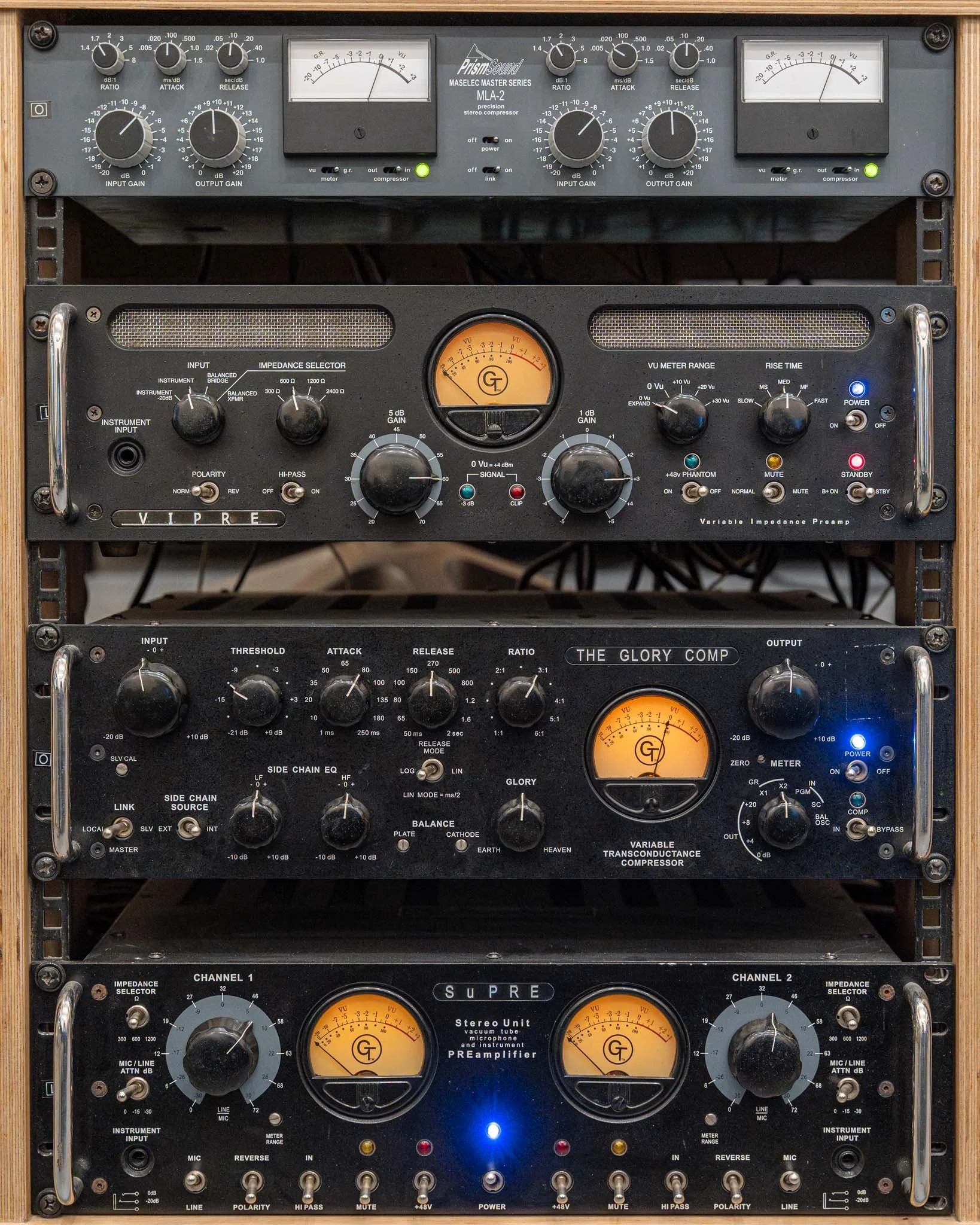 Three vintage audio equipment units stacked vertically, including a preamp, compressor, and stereo unit with knobs, meters, and switches.