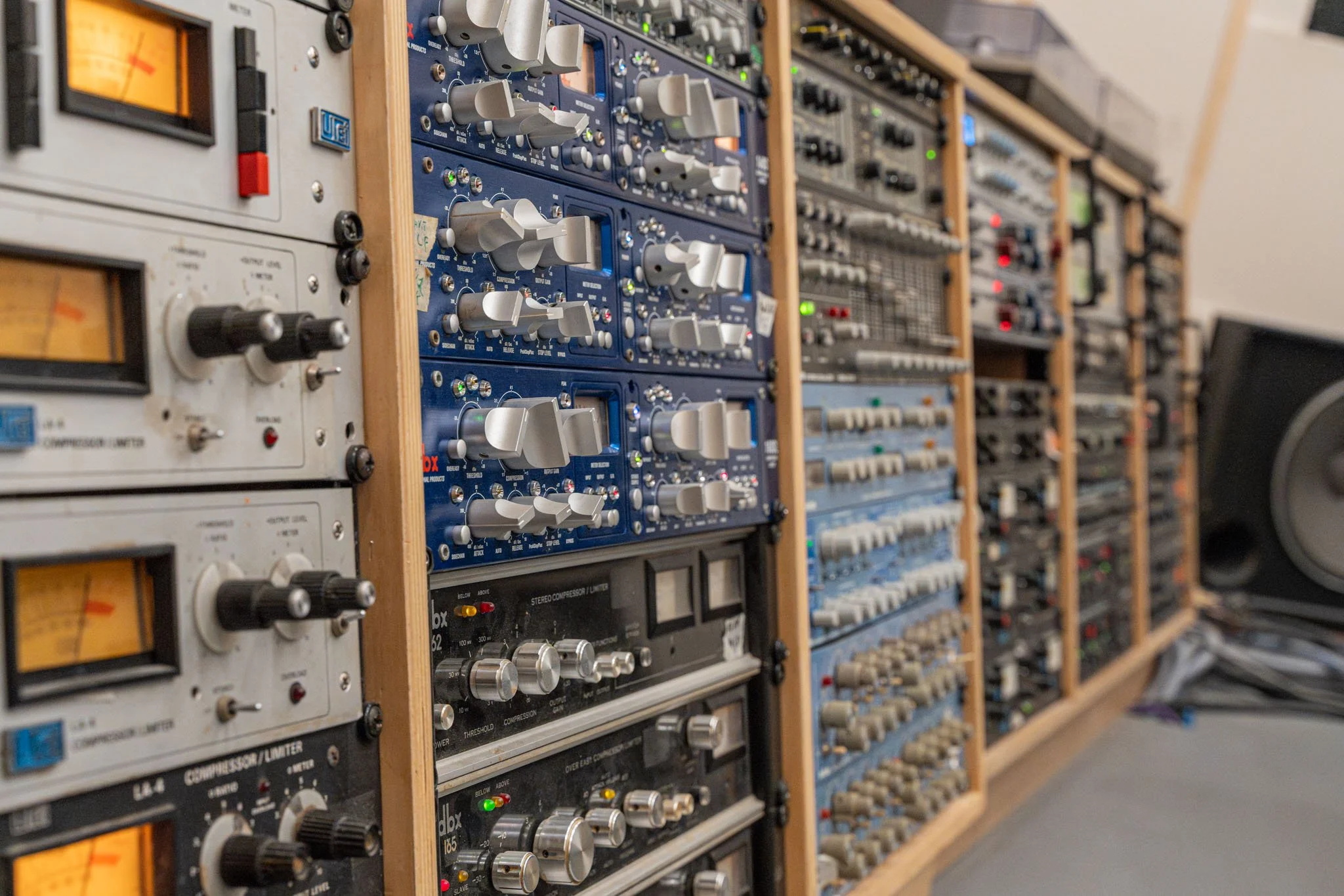 Audio equipment racks filled with compressors and audio processing units in a recording studio.
