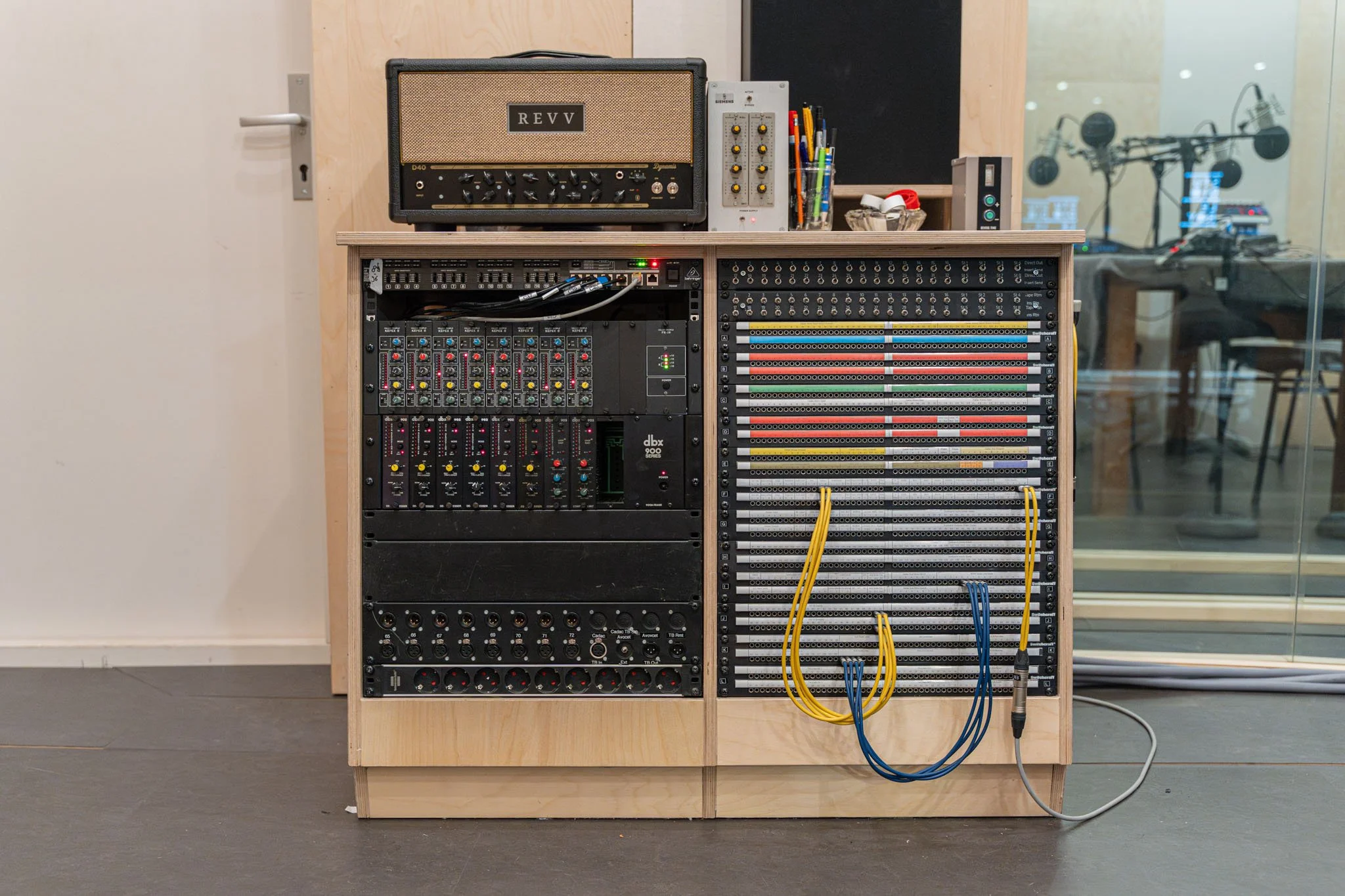 Audio mixing console with various equipment and cables inside a music studio.
