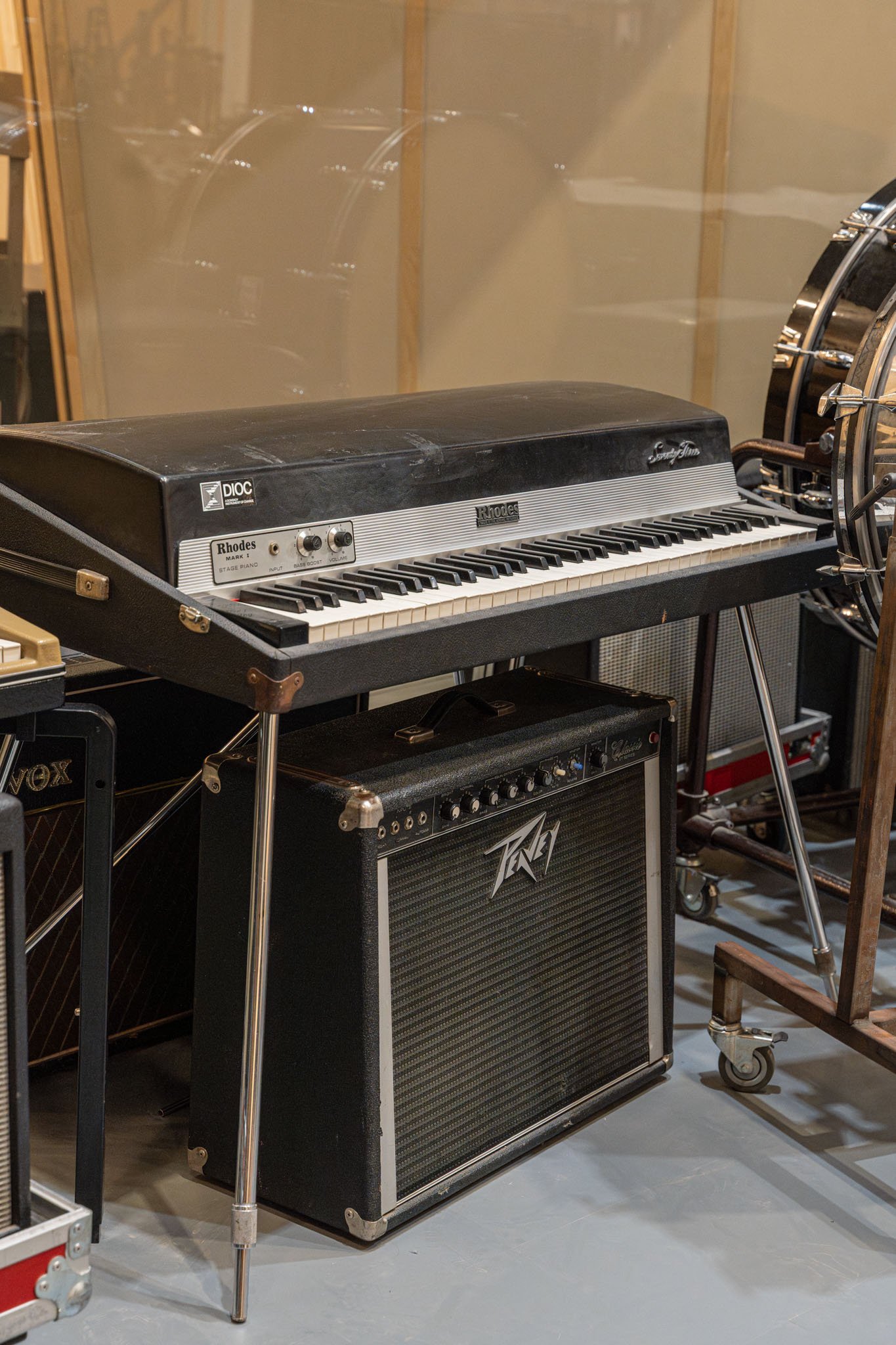Vintage Rhodes electric stage piano on a stand with a  guitar amplifier below, in a music studio.