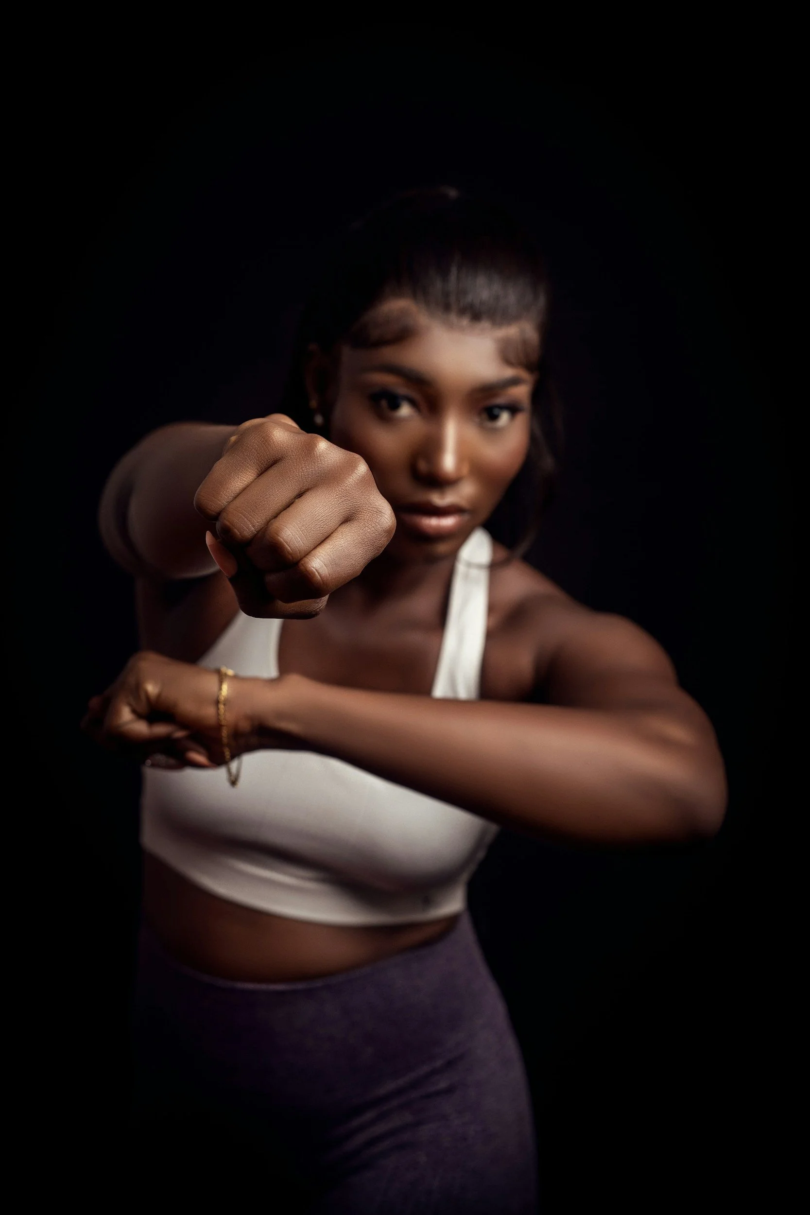 A woman in a fighting stance. The woman is taking a self defense class through Black Ridge Defense.