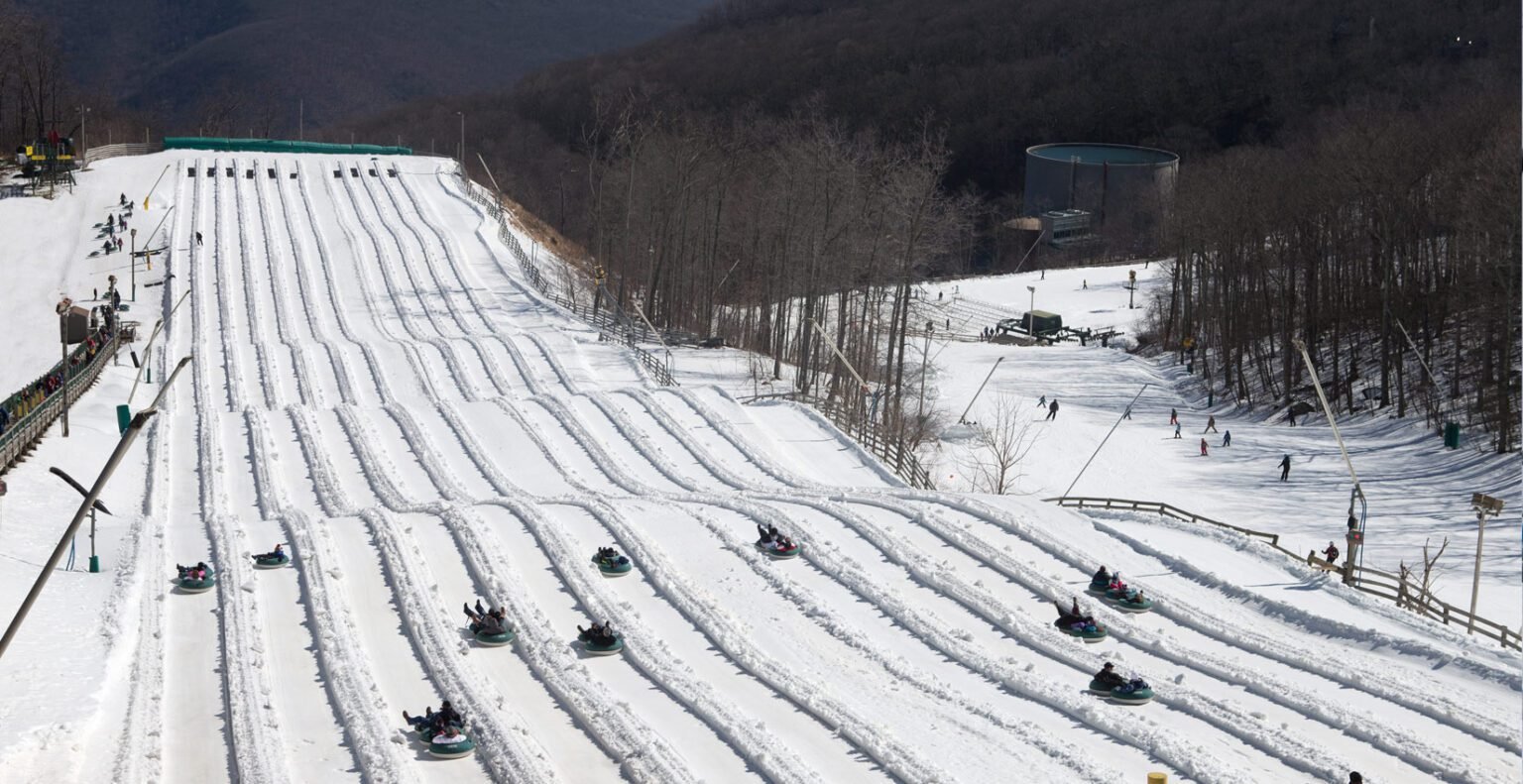 People riding snow tubes down a snowy hill at a winter resort.