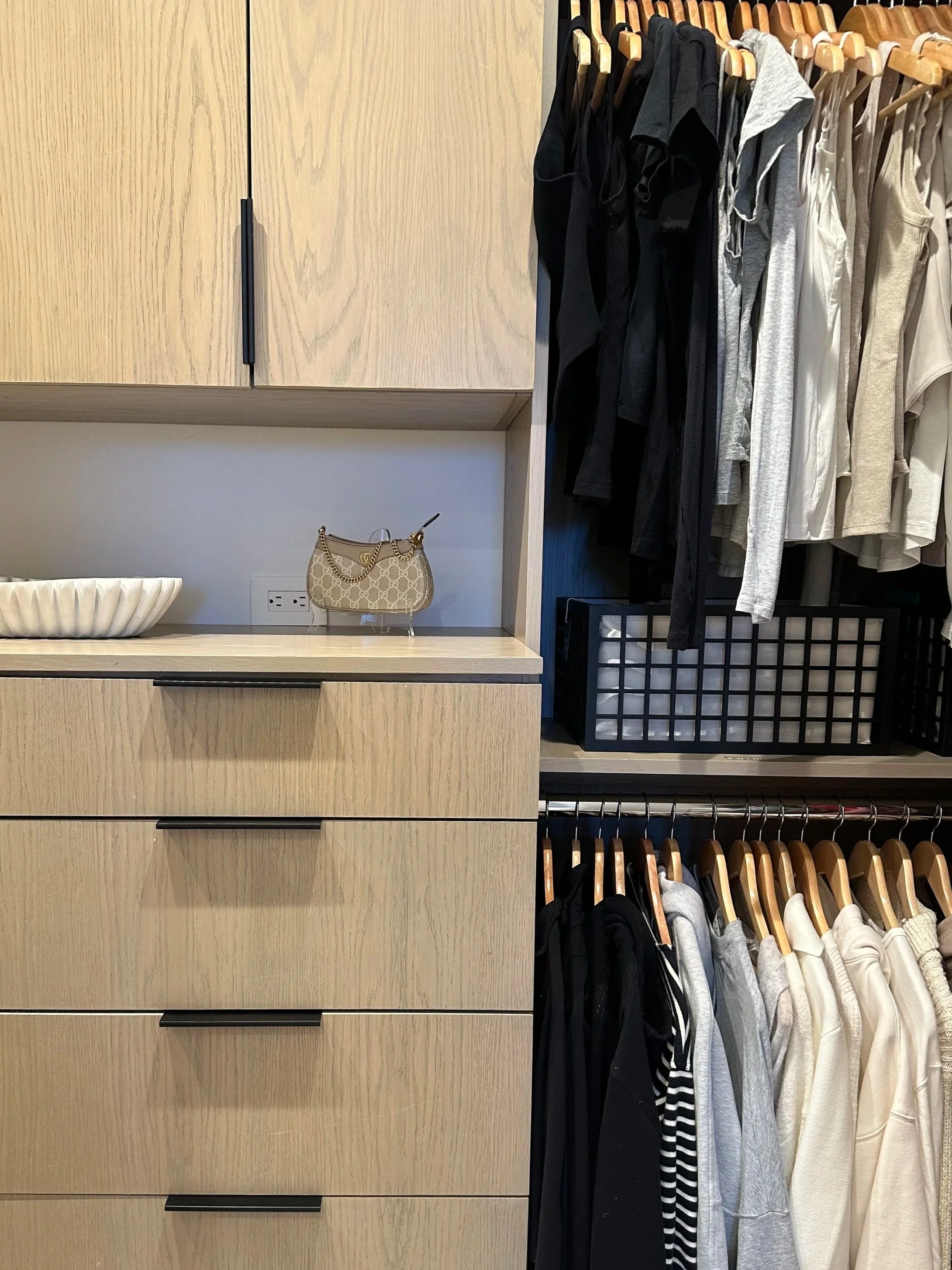 Glass jars with wooden lids containing pasta and grains on a kitchen shelf.