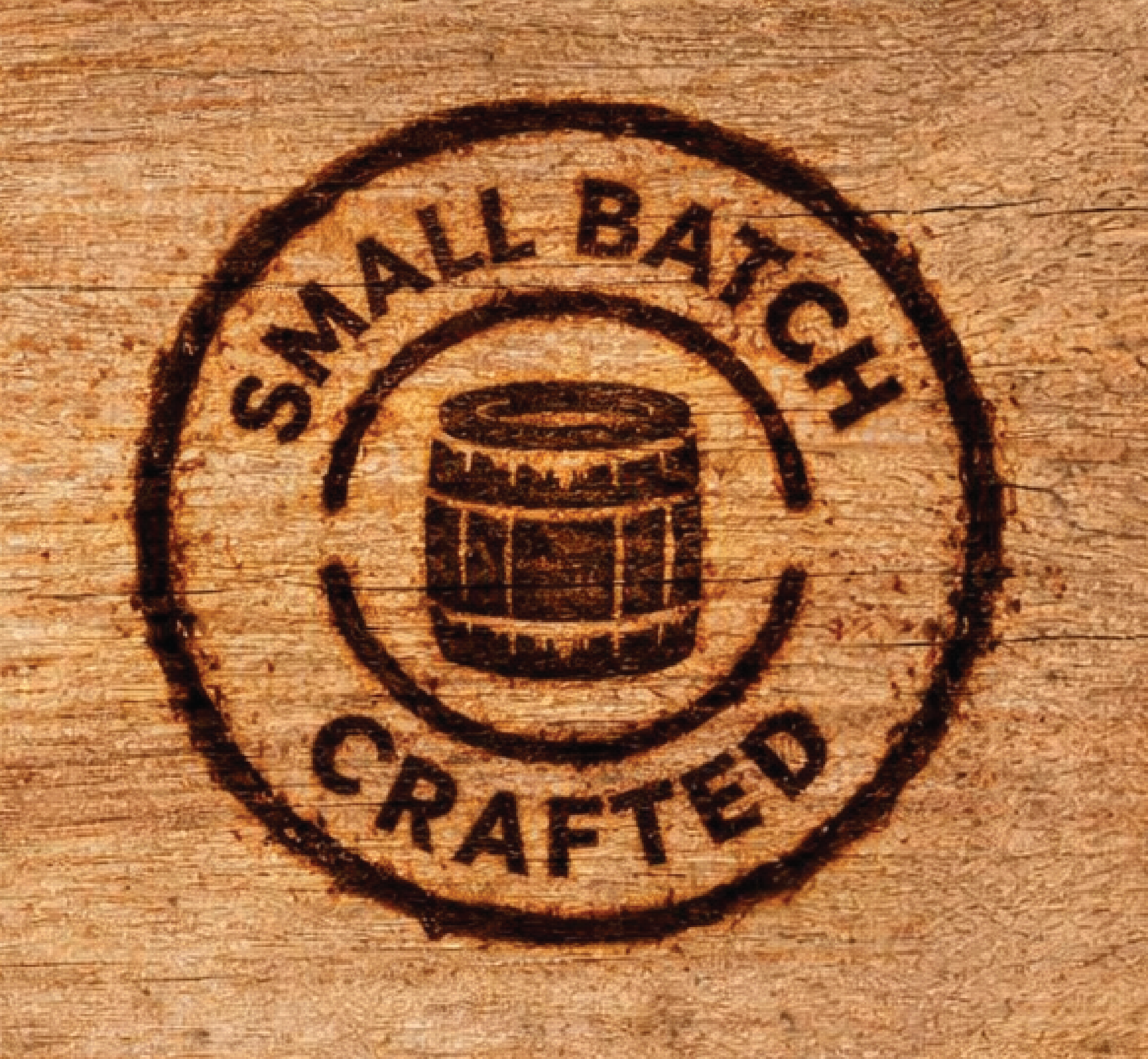 A circular stamp on wooden surface with the words 'Small Batch' and 'Crafted,' and a barrel illustration in the center.