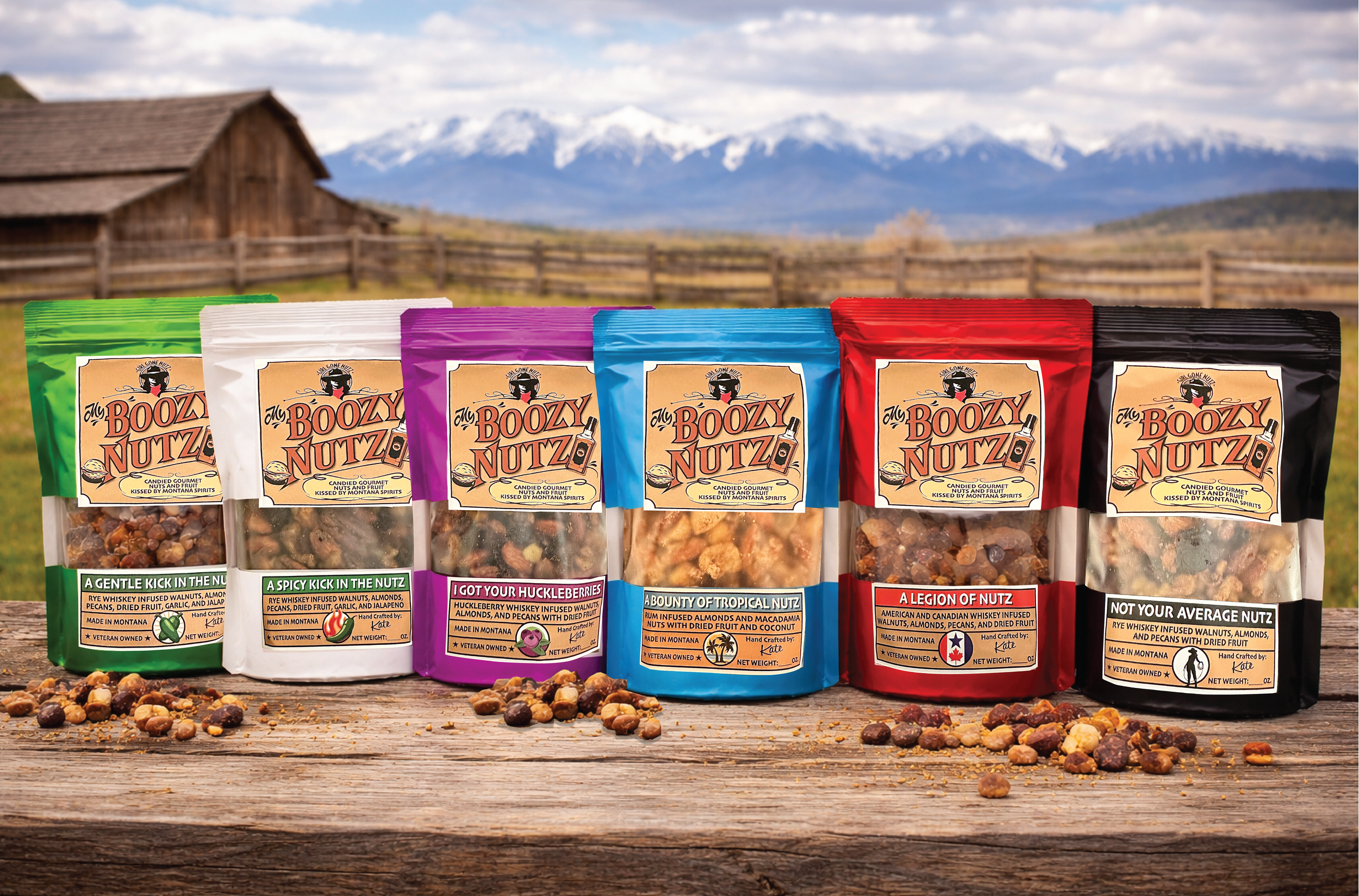 Six colorful bags of nut snacks on a wooden surface with scattered nuts, mountains, and a rustic building in the background.