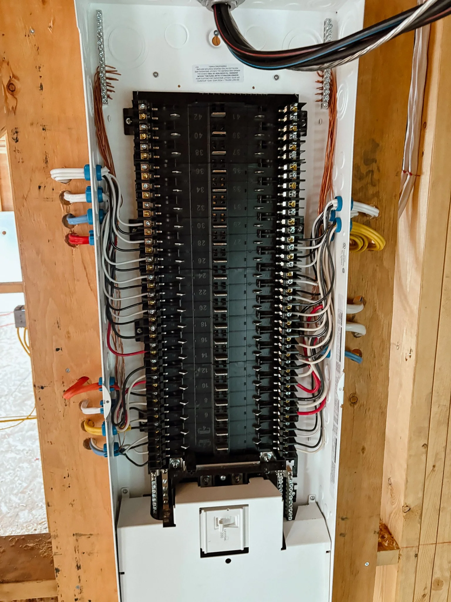 Open electrical breaker box with multiple circuit breakers and wiring.