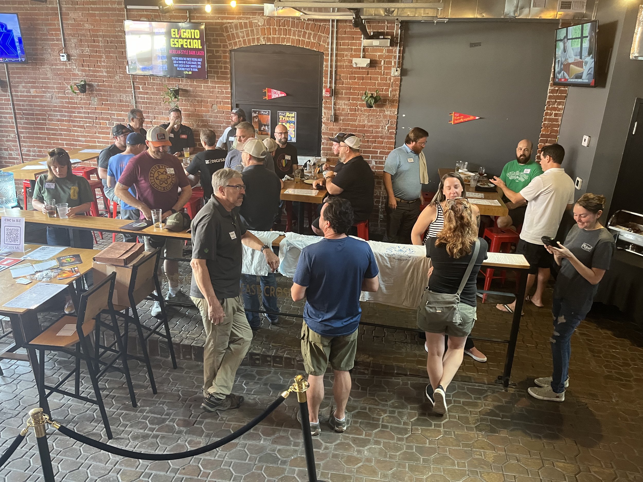 group of women and men gathered in a brewery space for a networking event