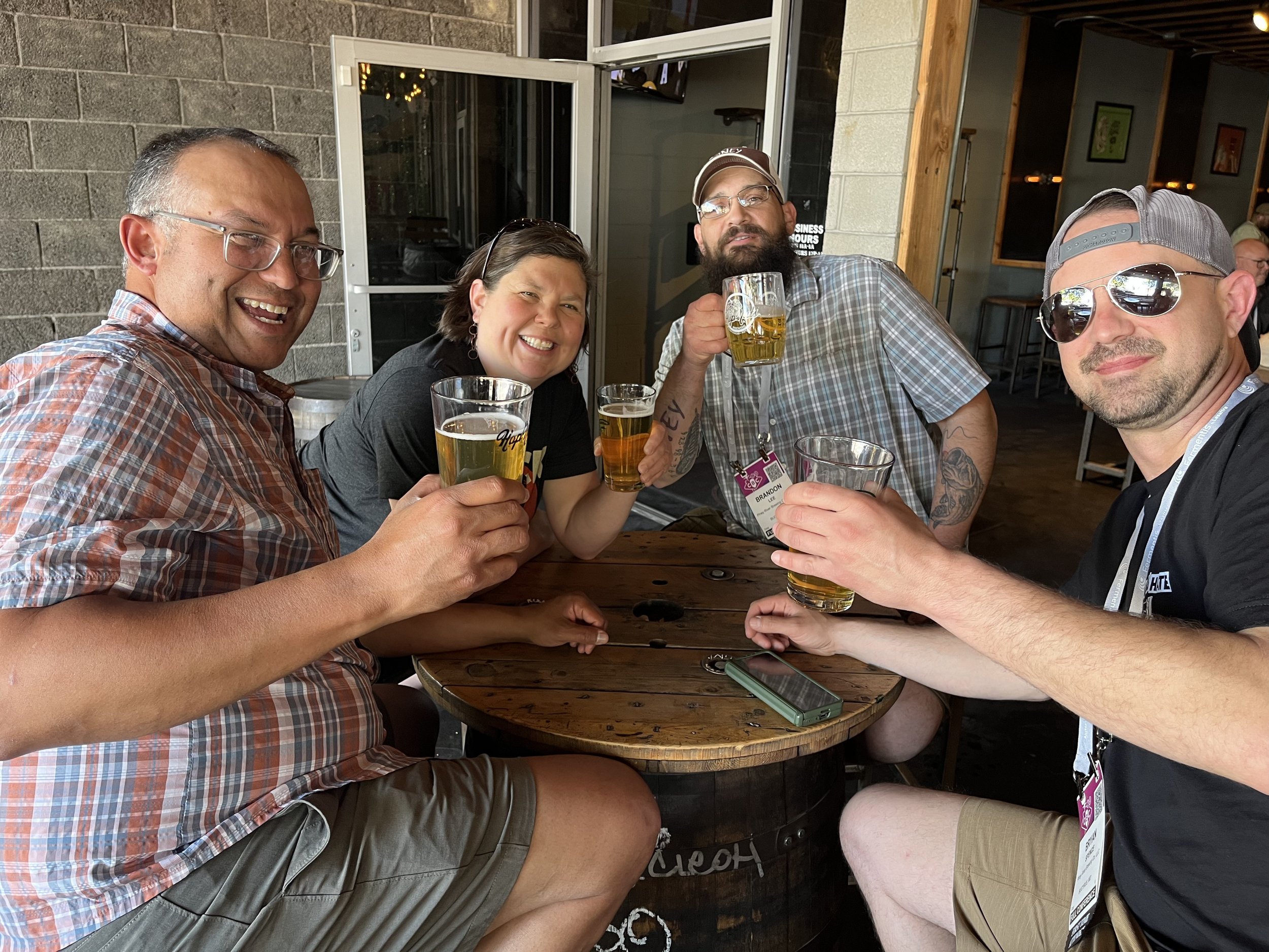 a group of four people hold their beers up in cheers at a guild gathering