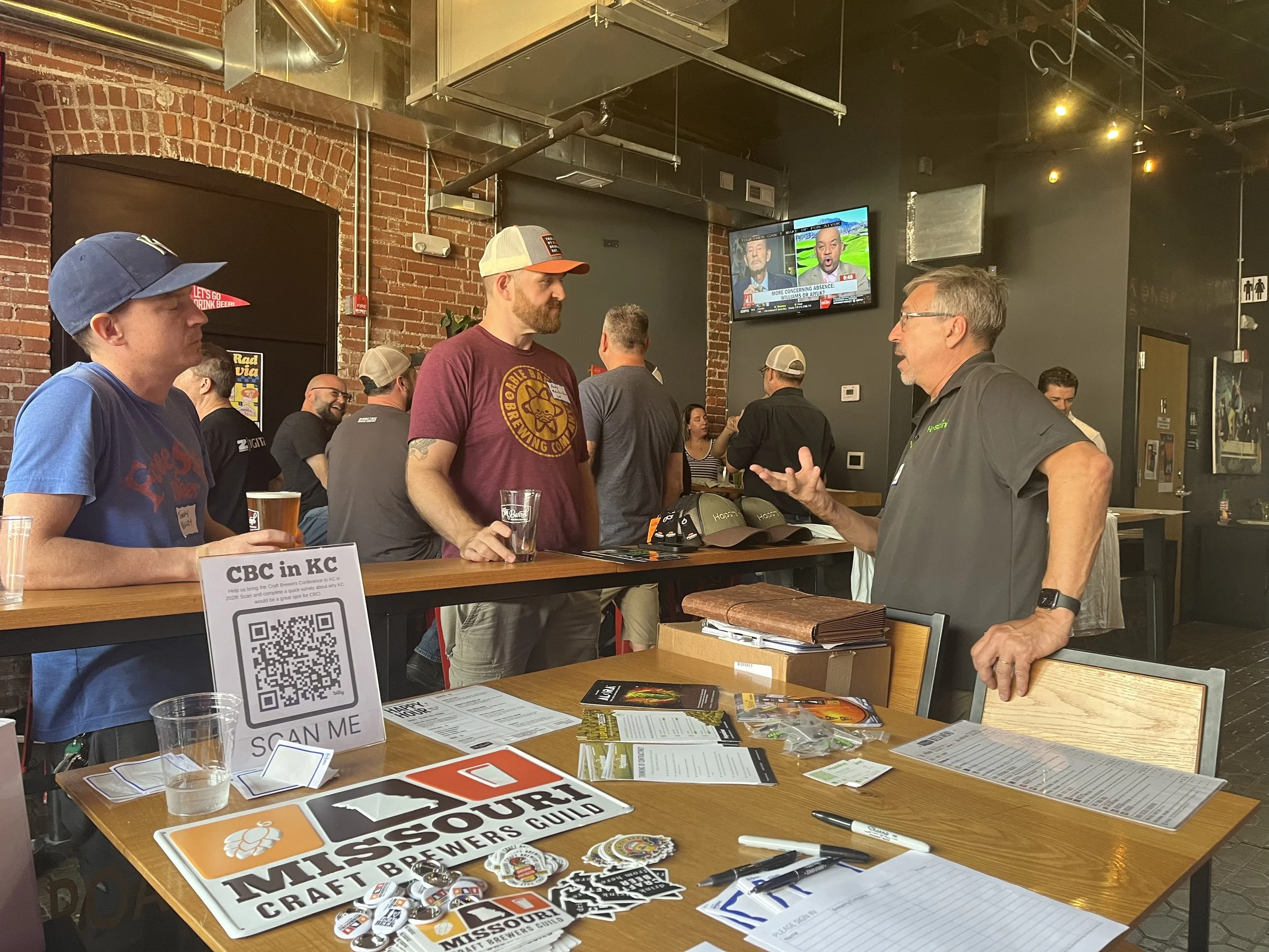 one man listens intently as another man is talking among a group of people at a social gathering