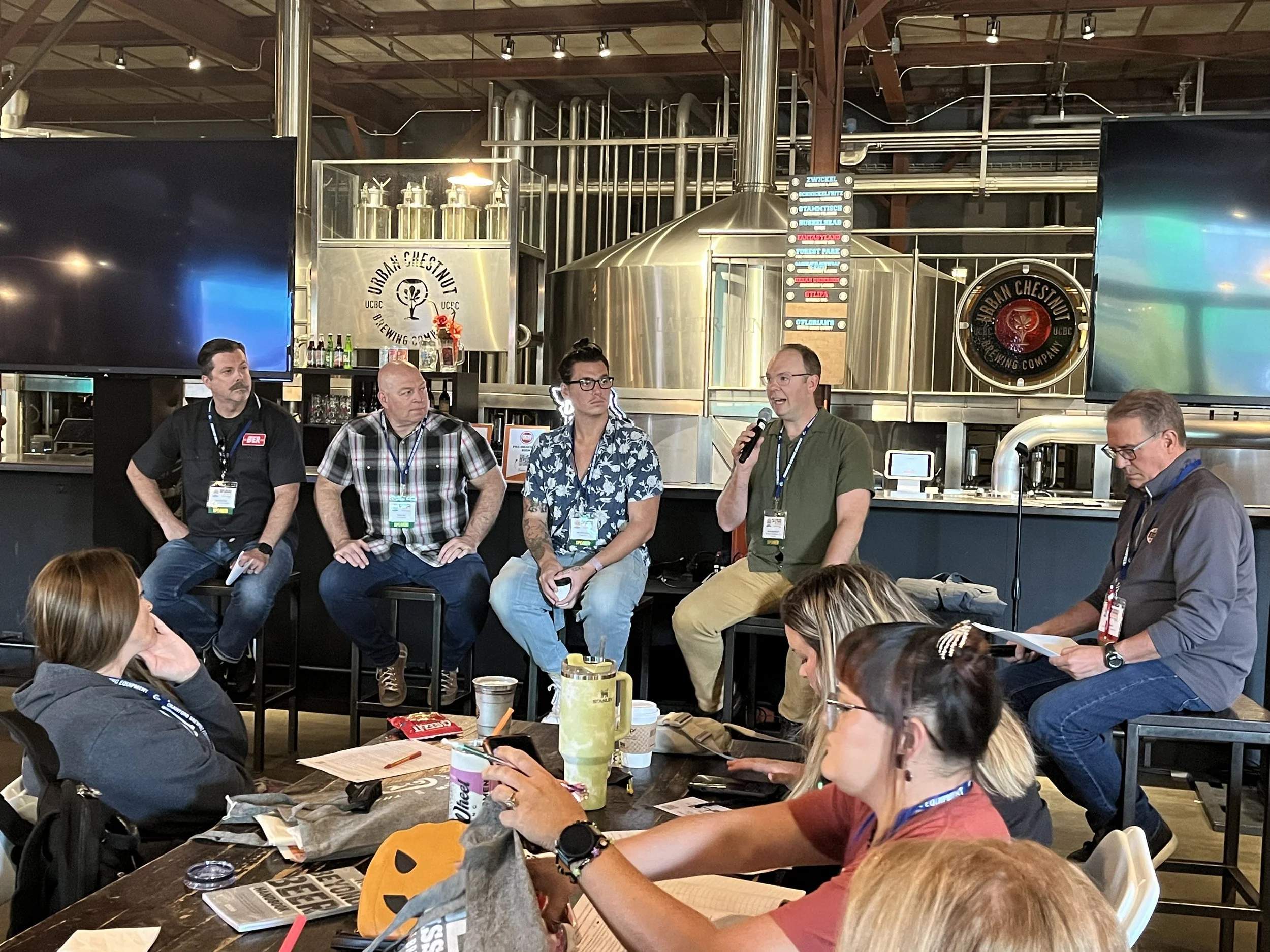 a panel group of five sit at the front of a room for a discussion on beer sales during the annual conference
