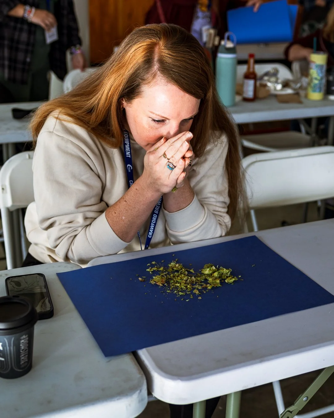 a woman holds her hands up to her nose to smell rubbed hops at the conference