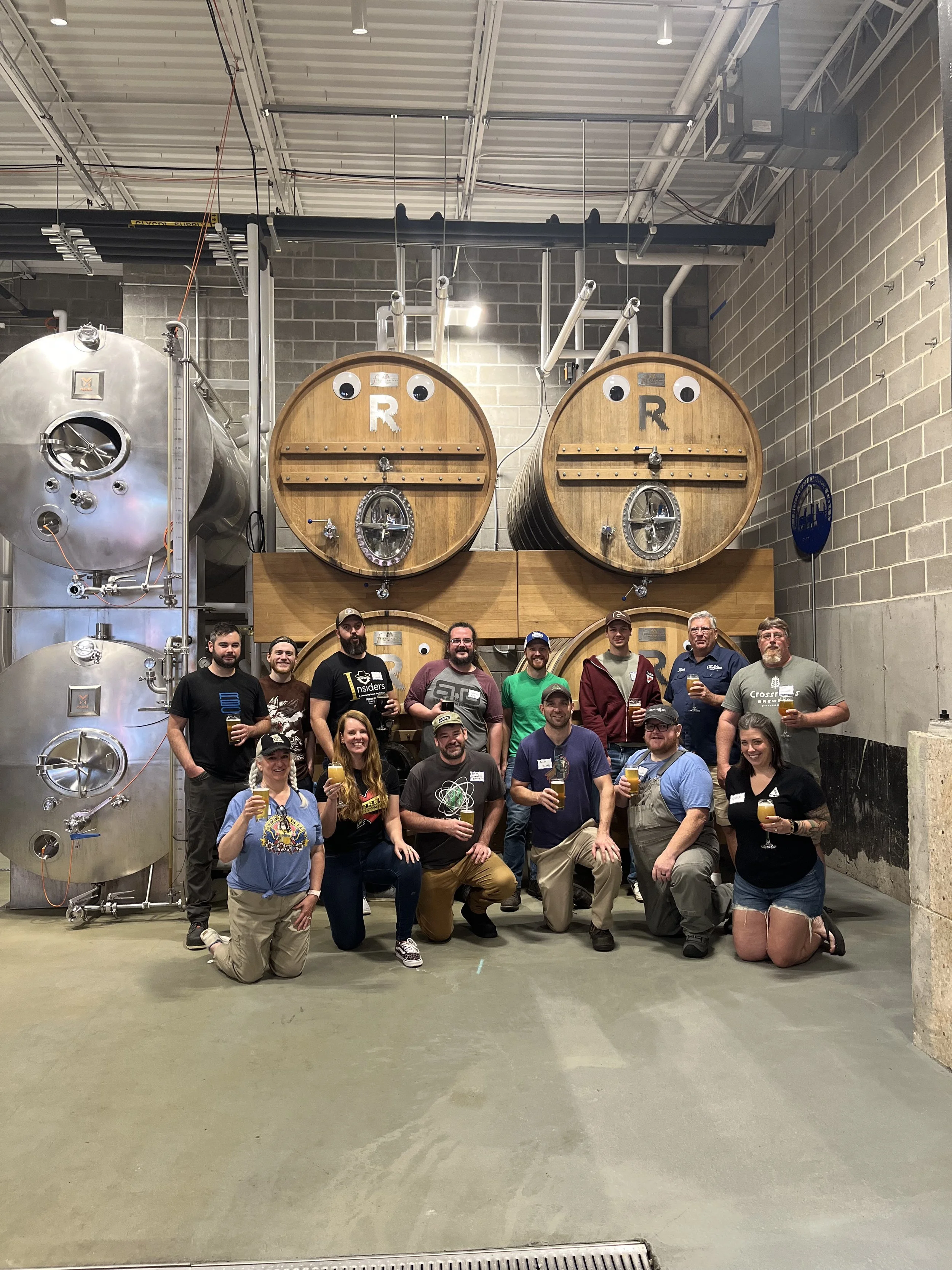 Group of women and men posed together at rockwell beer company in front of their oak foeders.