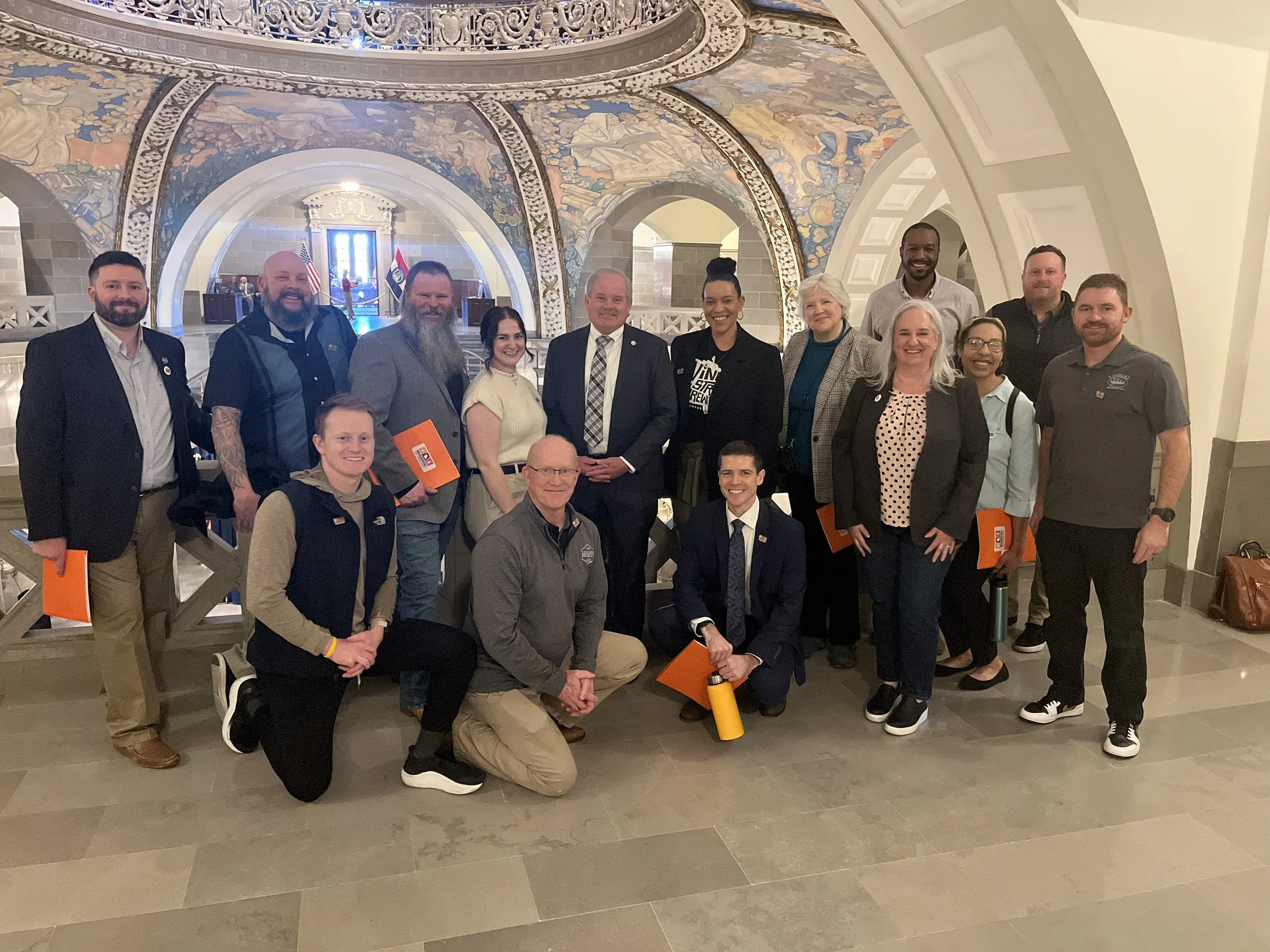 group of women and men posed together in the mezannine at the missouri state capitol with a member of the missouri house of representatives