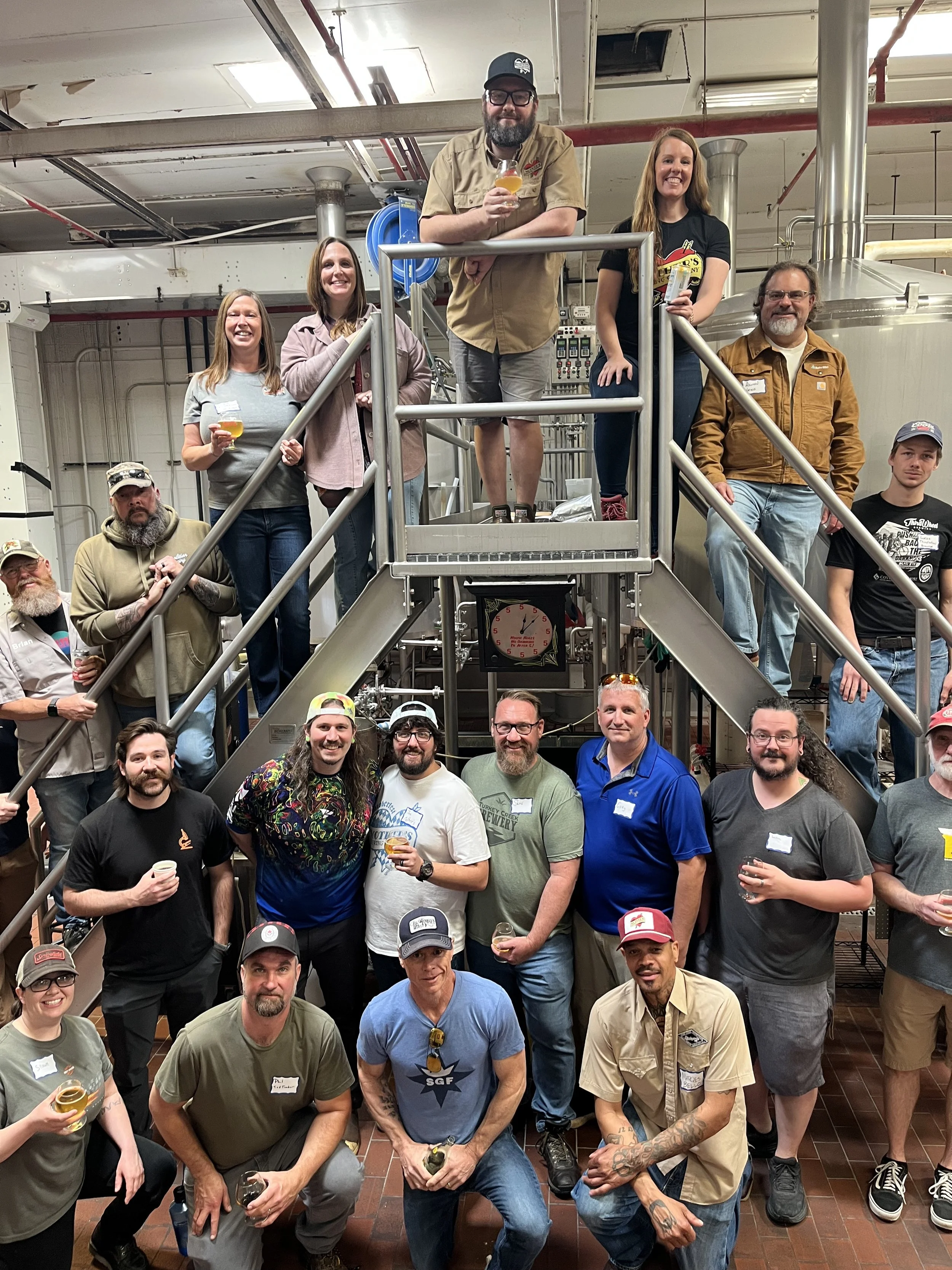 Group of people posed on the brewing equipment at Mother's Brewing Company