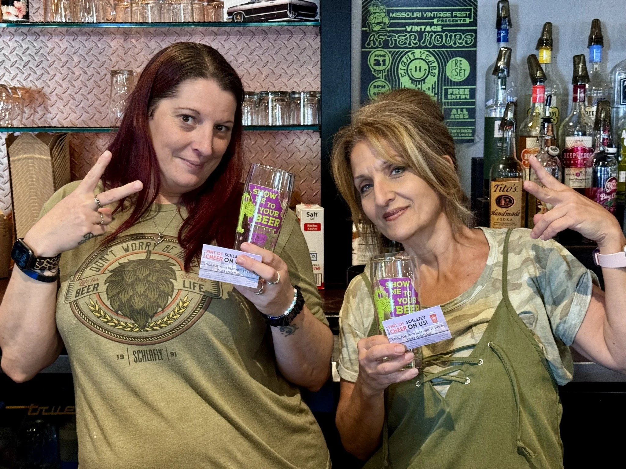 two brewery employees pose with the Missouri Pint Day glass and a coupon for a beer pour