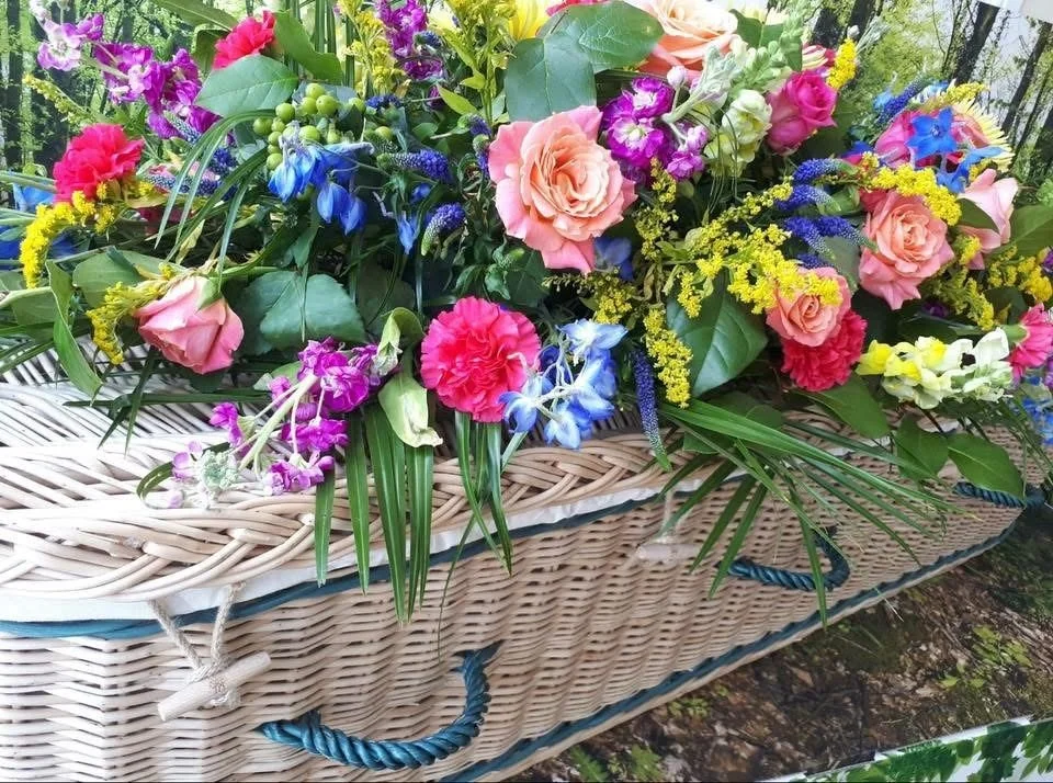 Vibrant funeral flowers with a wicker casket/coffin wigan florist