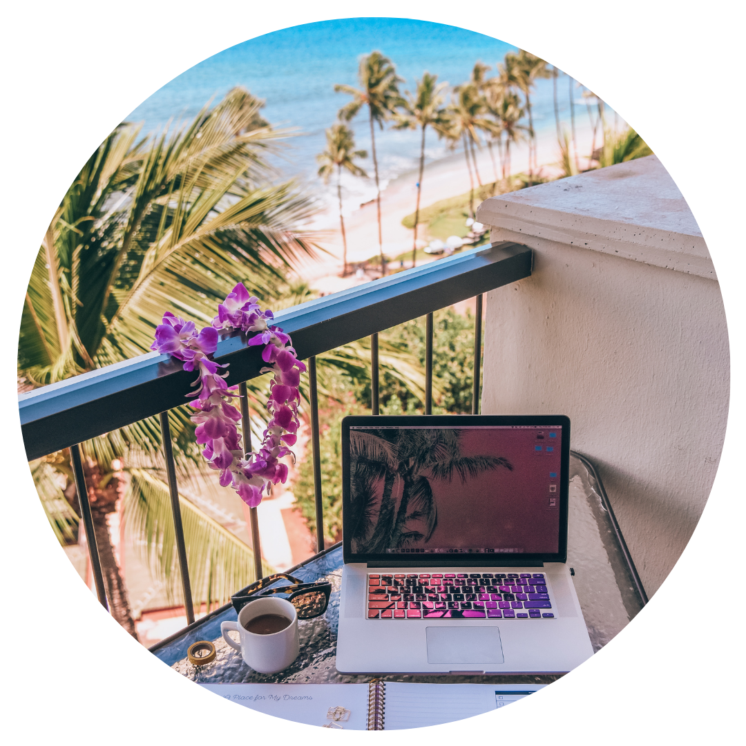 A laptop, coffee, and planner on a balcony with ocean and palm trees in the background.