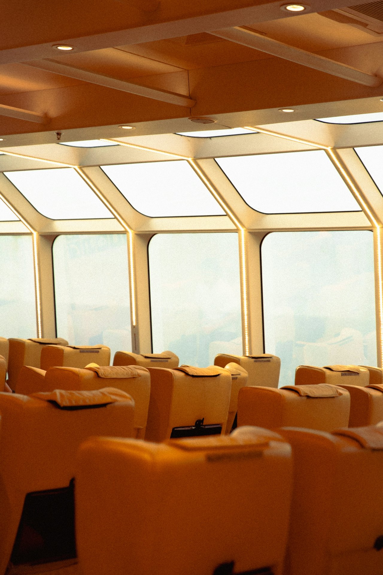 Empty airplane passenger cabin with yellow seats and large windows.