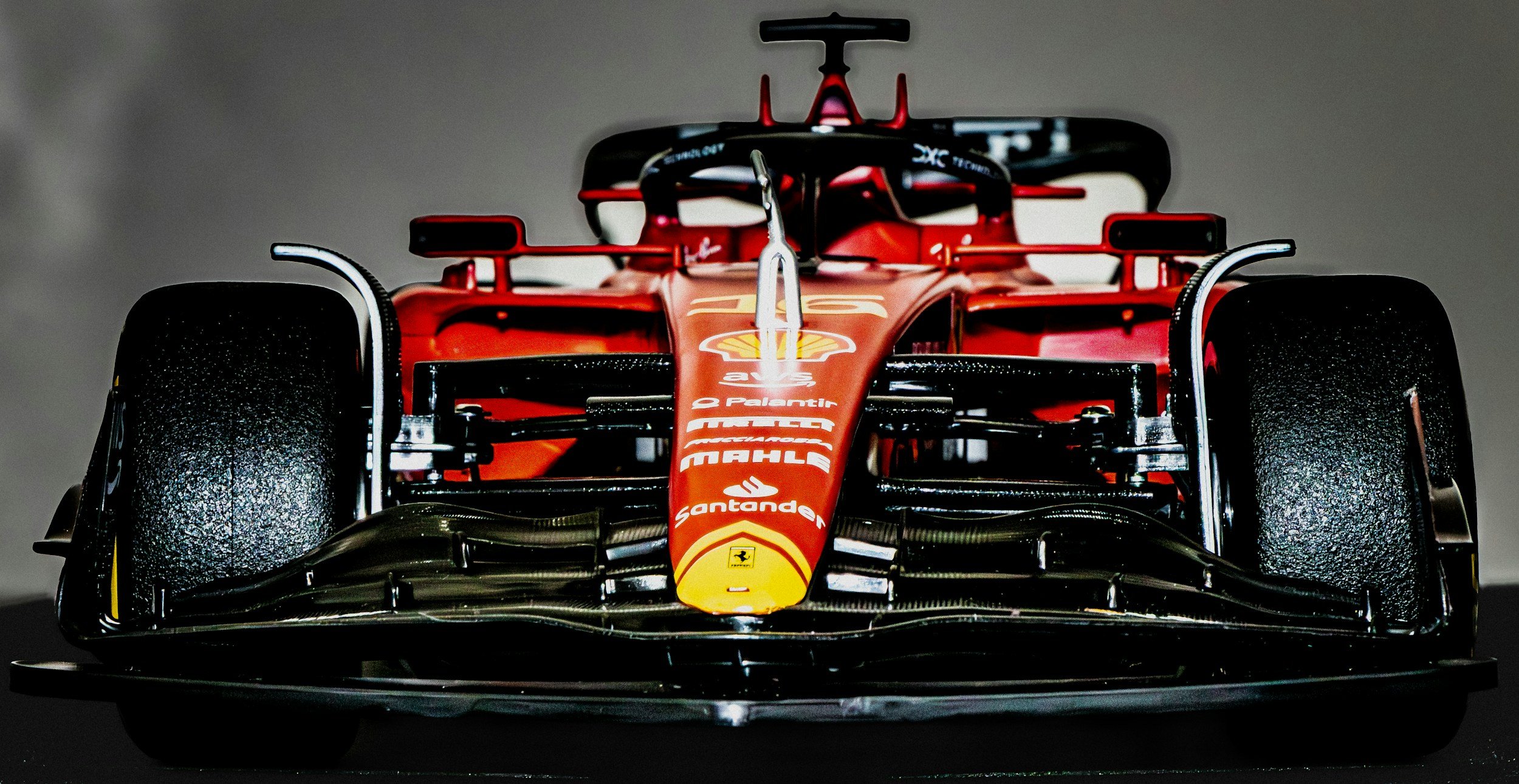 Front view of a red Formula 1 race car with visible sponsor logos, including Ferrari and Santander, on a dark background.