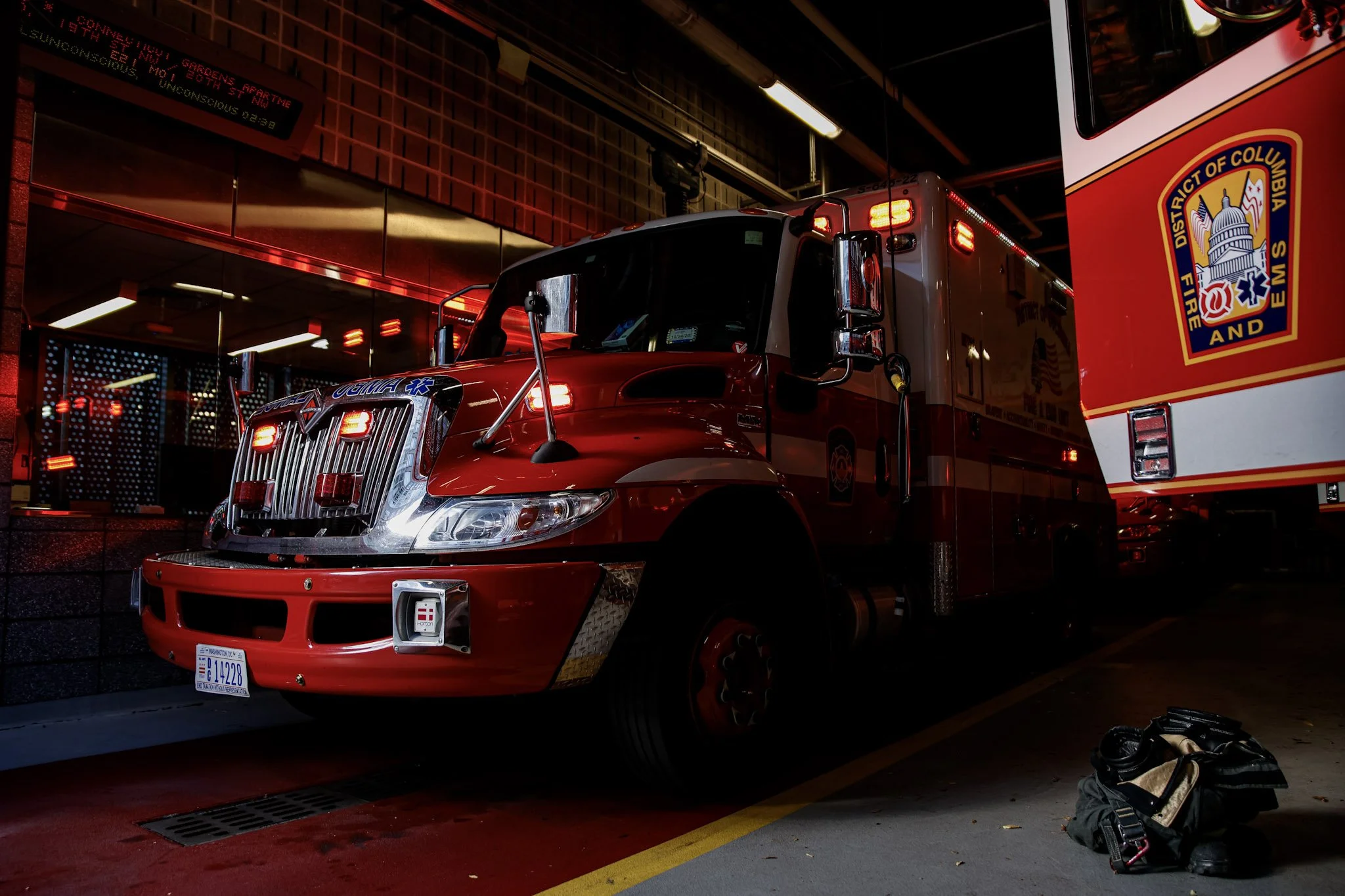 Fire truck parked inside a fire station, with a Columbus Fire and EMS emblem visible on a large red and white vehicle on the right.