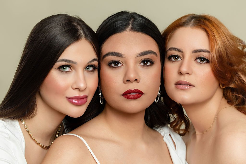 Three women with different hair colors and styles, posing close together for the camera in a portrait shot.