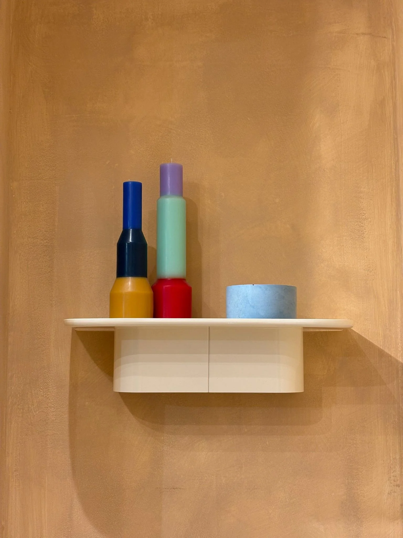 Decorative shelf with colorful nail polish bottles and a rolled-up blue towel on the wall.
