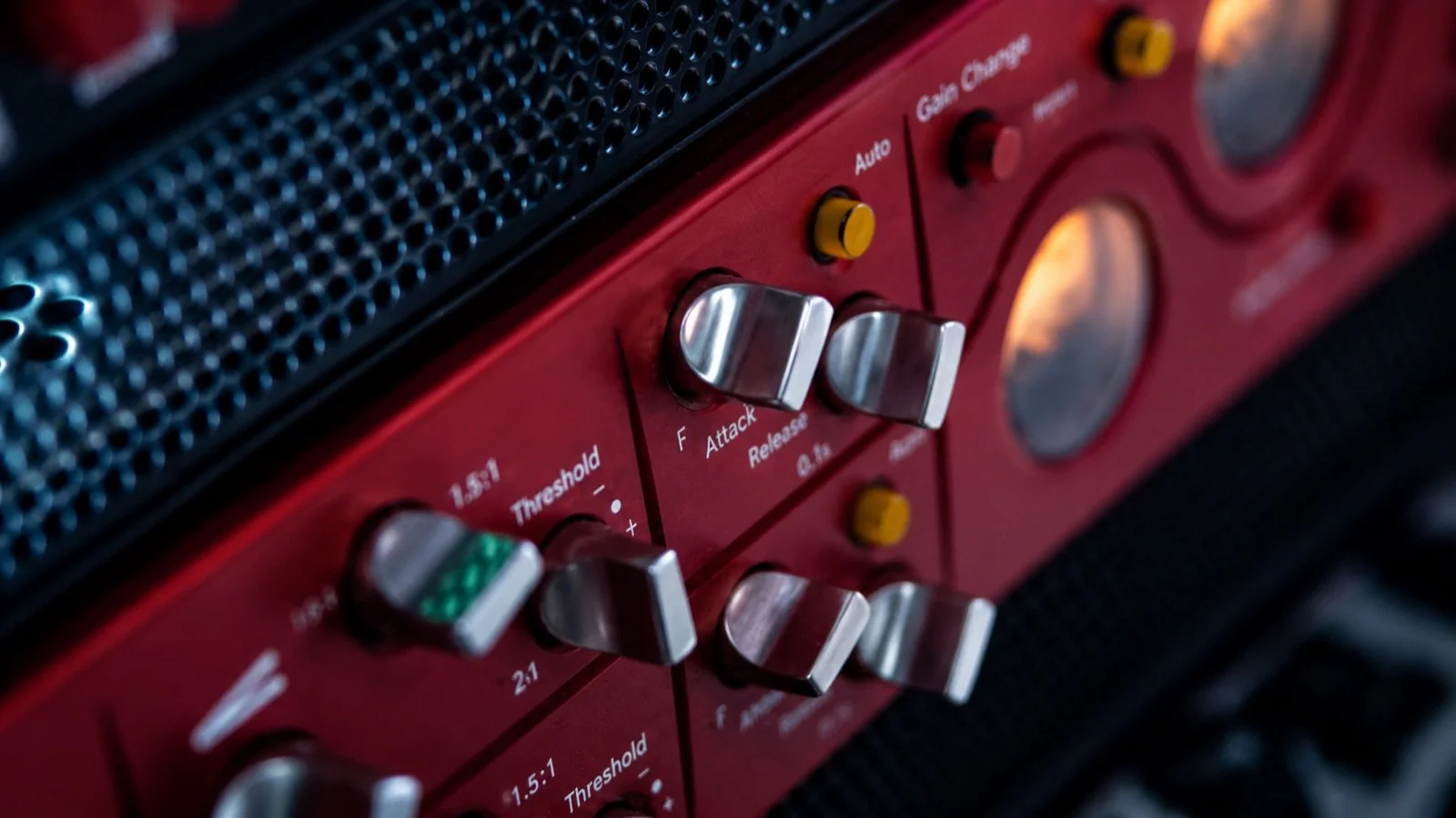 Close-up of a red audio mixer with silver and yellow knobs and a black speaker grill on top.
