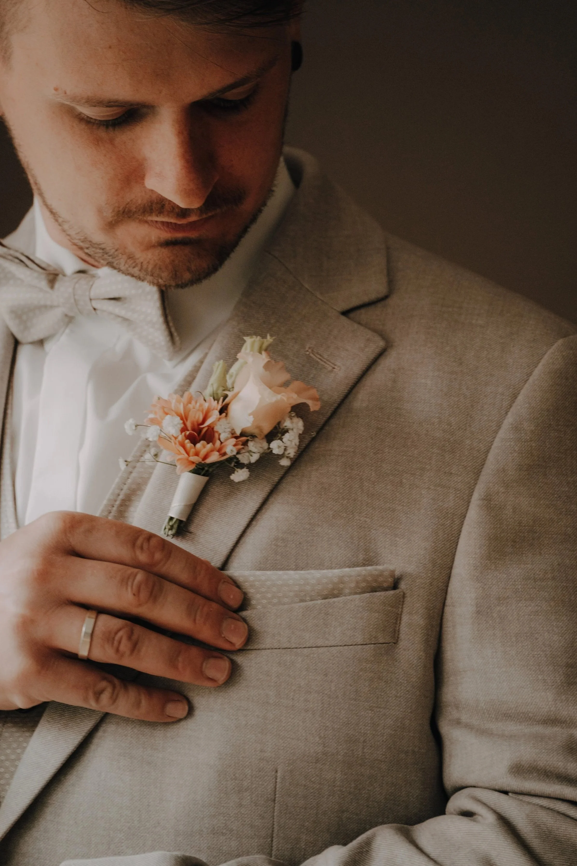 Nahaufnahme eines Mannes in einem Anzug mit Blumenanstecknadel auf der Brusttasche.