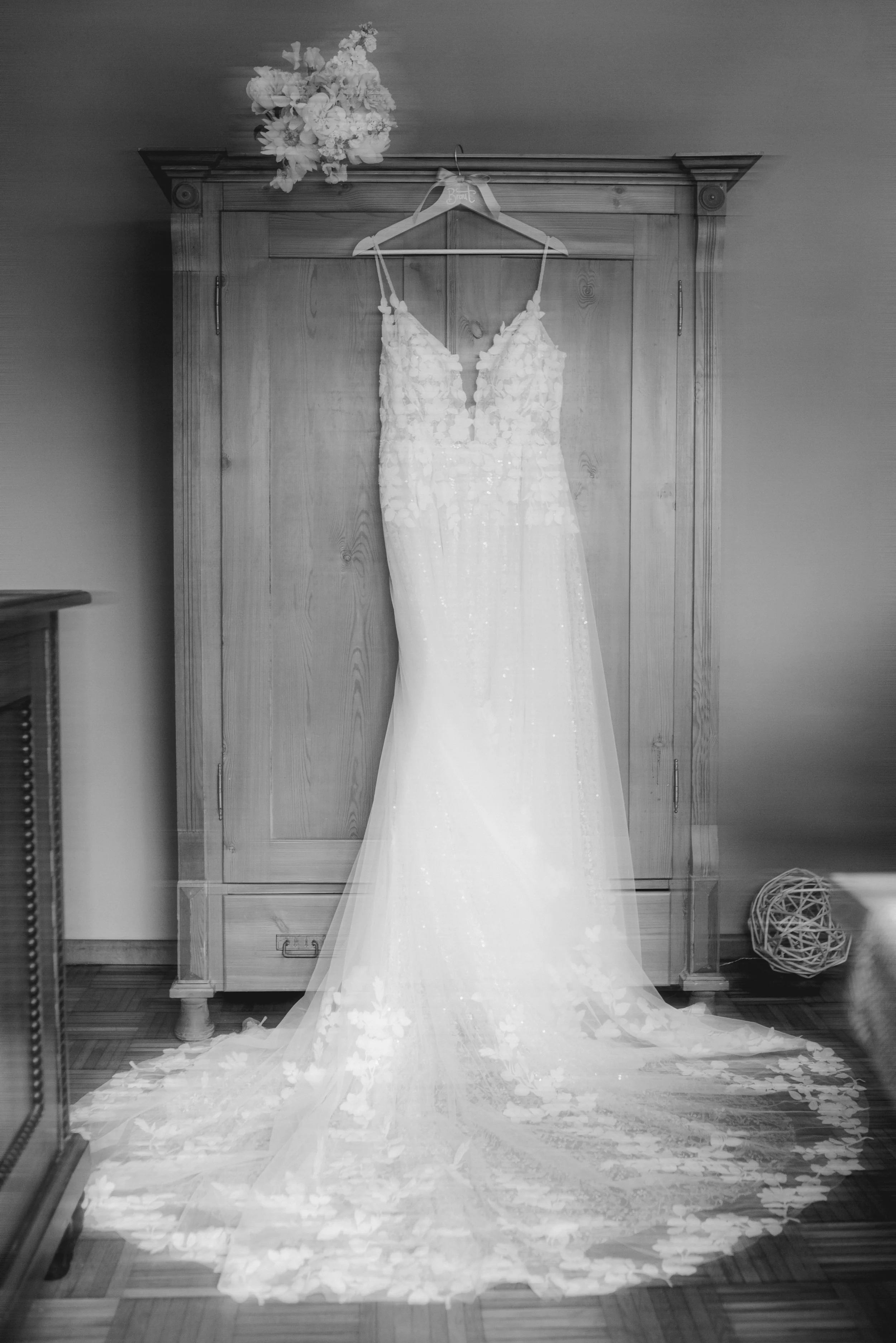 Weiße Brautkleid mit Blumenmuster auf dem Boden und vor einem Holzwand