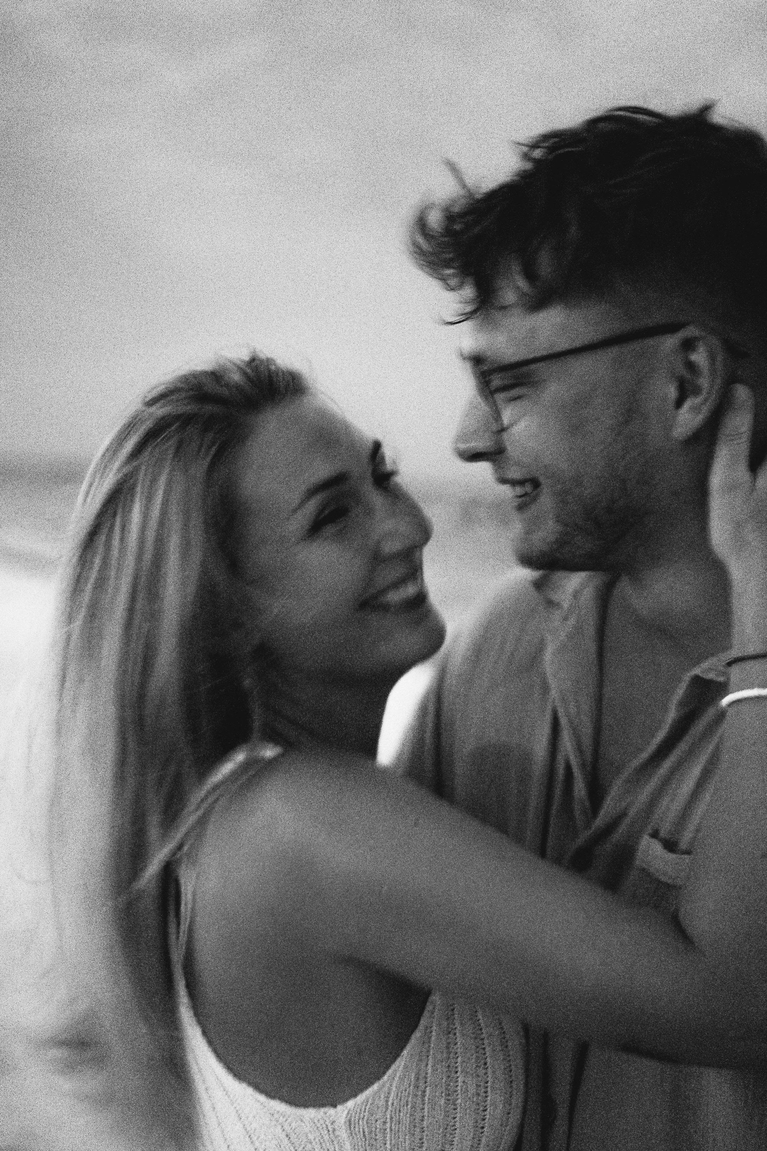 Ein lachendes Paar, das sich liebevoll umarmt, in Schwarz-Weiß-Fotografie.