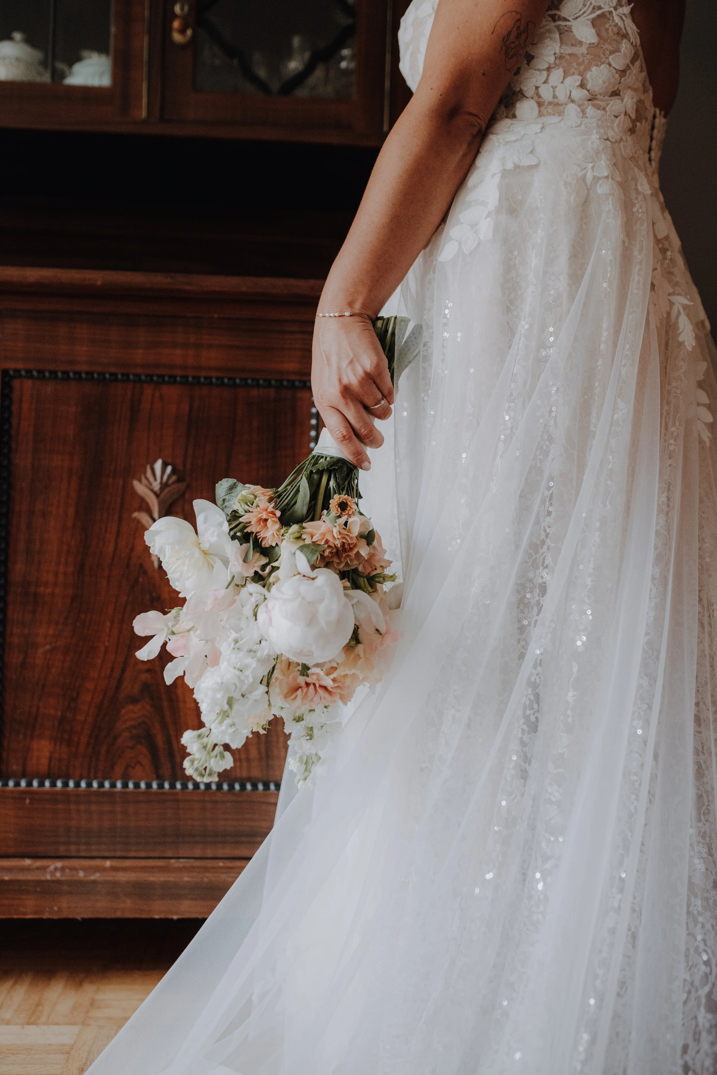 Nahaufnahme einer Braut in einem weißen Kleid, die einen Blumenstrauß hält.
