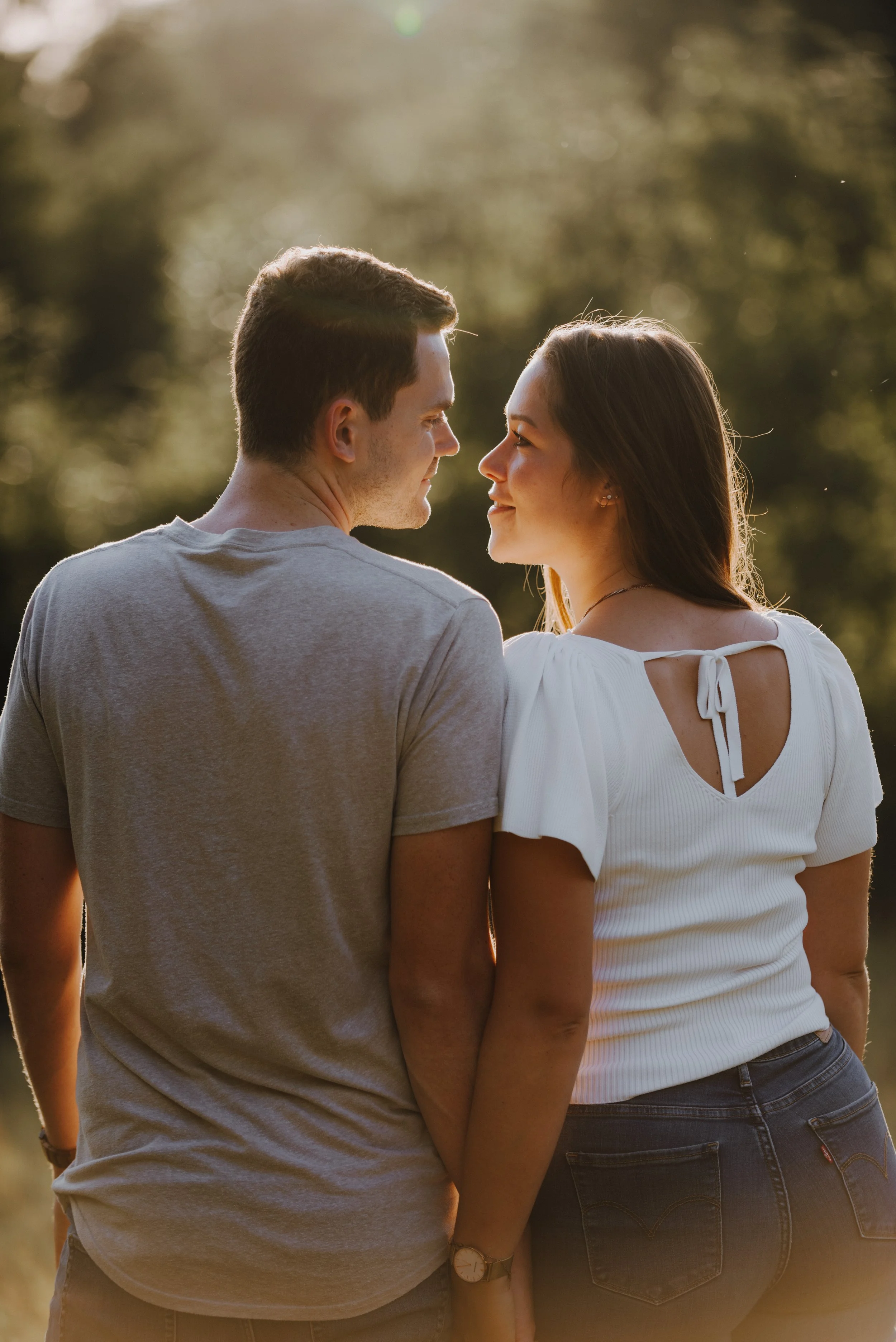 Ein Mann und eine Frau stehen sich in der Natur gegenüber, schauen sich liebevoll an, bei Sonnenuntergang.
