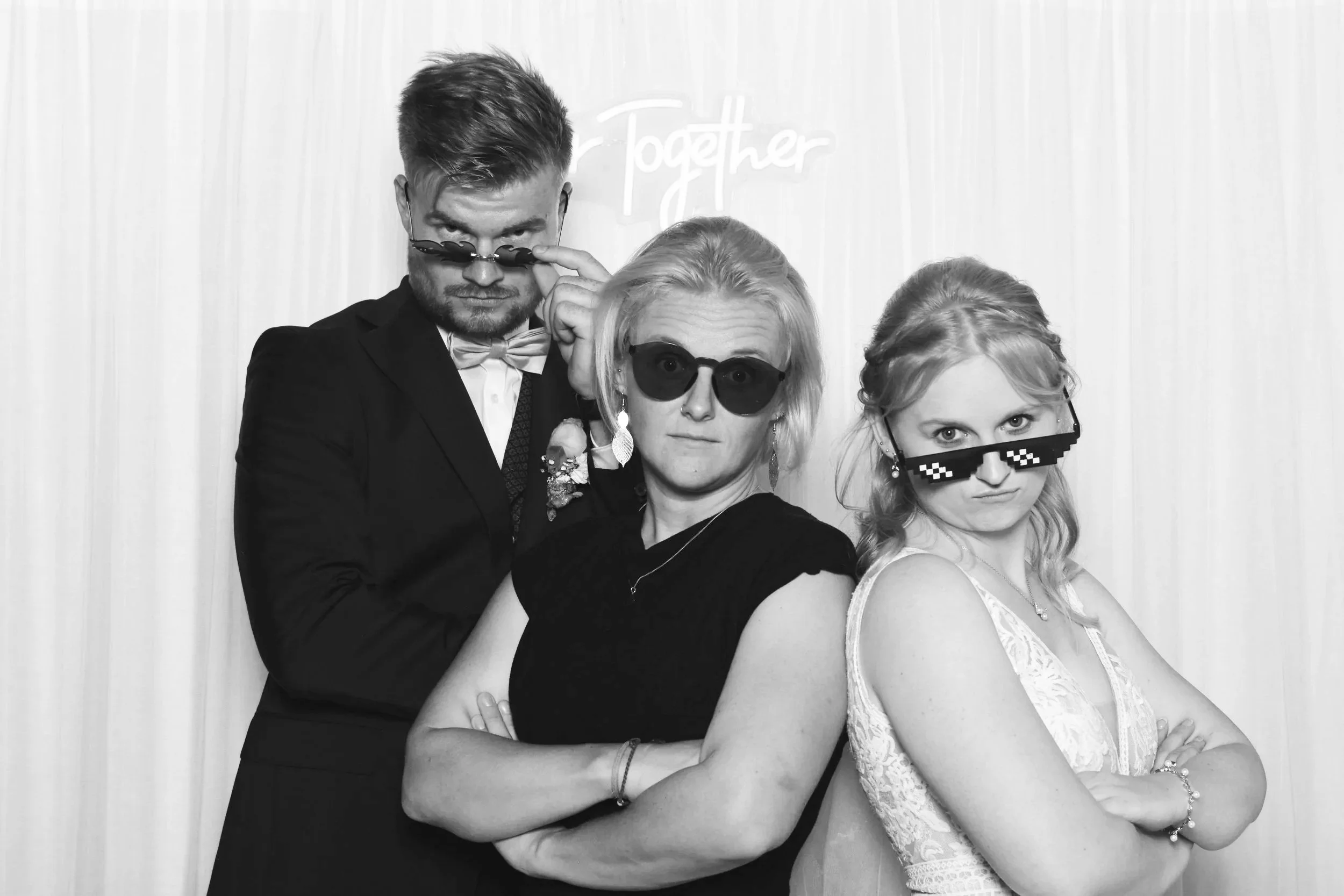 Drei junge Erwachsene mit Sonnenbrillen, die auf eine humorvolle Weise posieren, vor einem weißen Hintergrund mit dem Wort „Together“.