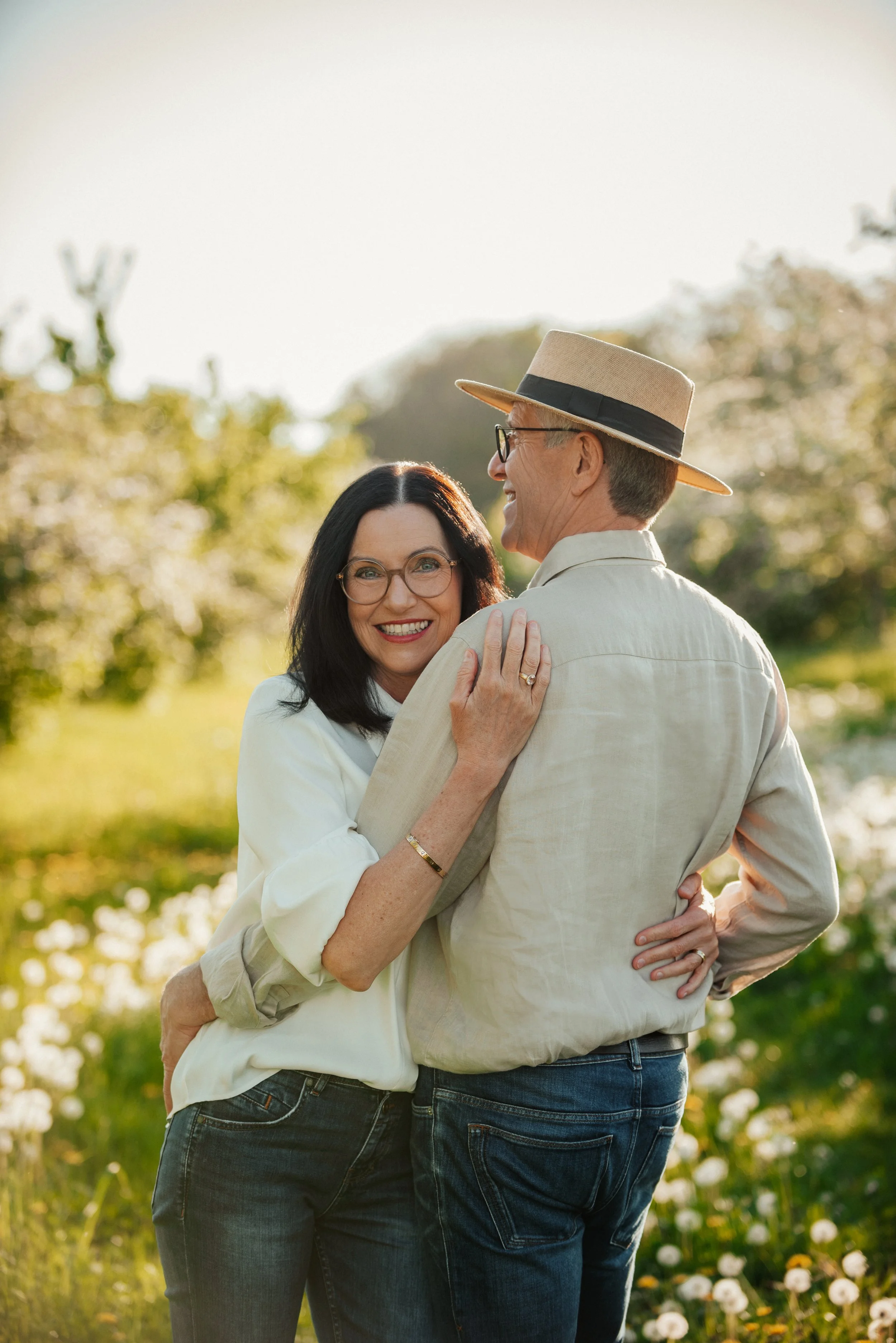 Ein glückliches Pärchen, das sich im Freien umarmt, bei Sonnenuntergang in einer blühenden Natur