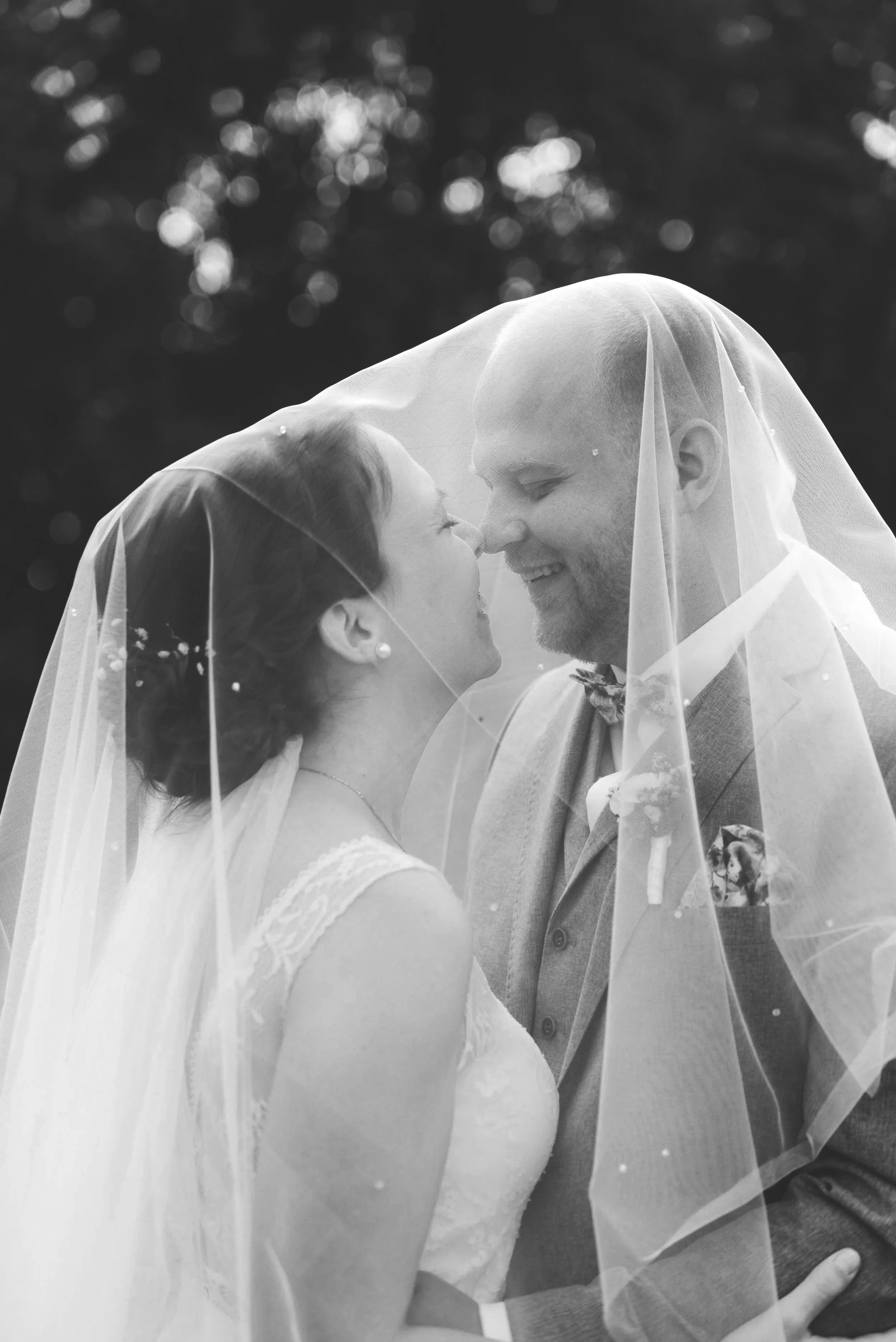 Braut und Bräutigam unter Brautveil bei Hochzeitsfotografie, schwarz-weiß, romantisches Paar in Liebe